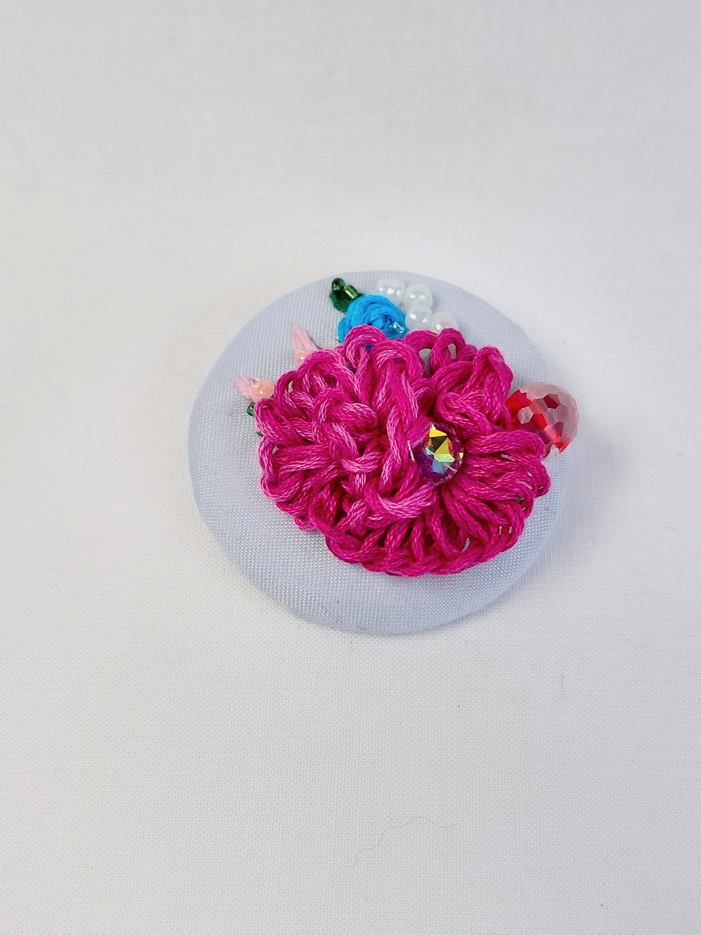Decorative fuschia flower brooch on light blue background