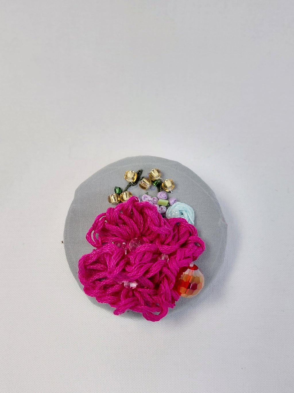 Decorative fuschia flower brooch on grey background