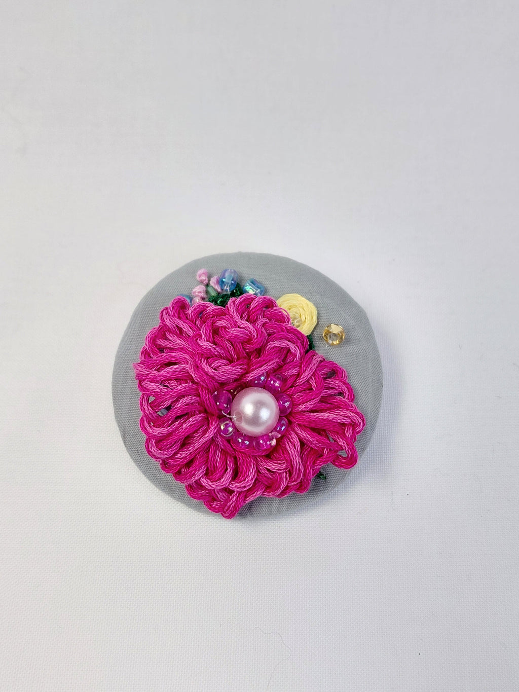 Decorative fuschia flower brooch on grey background