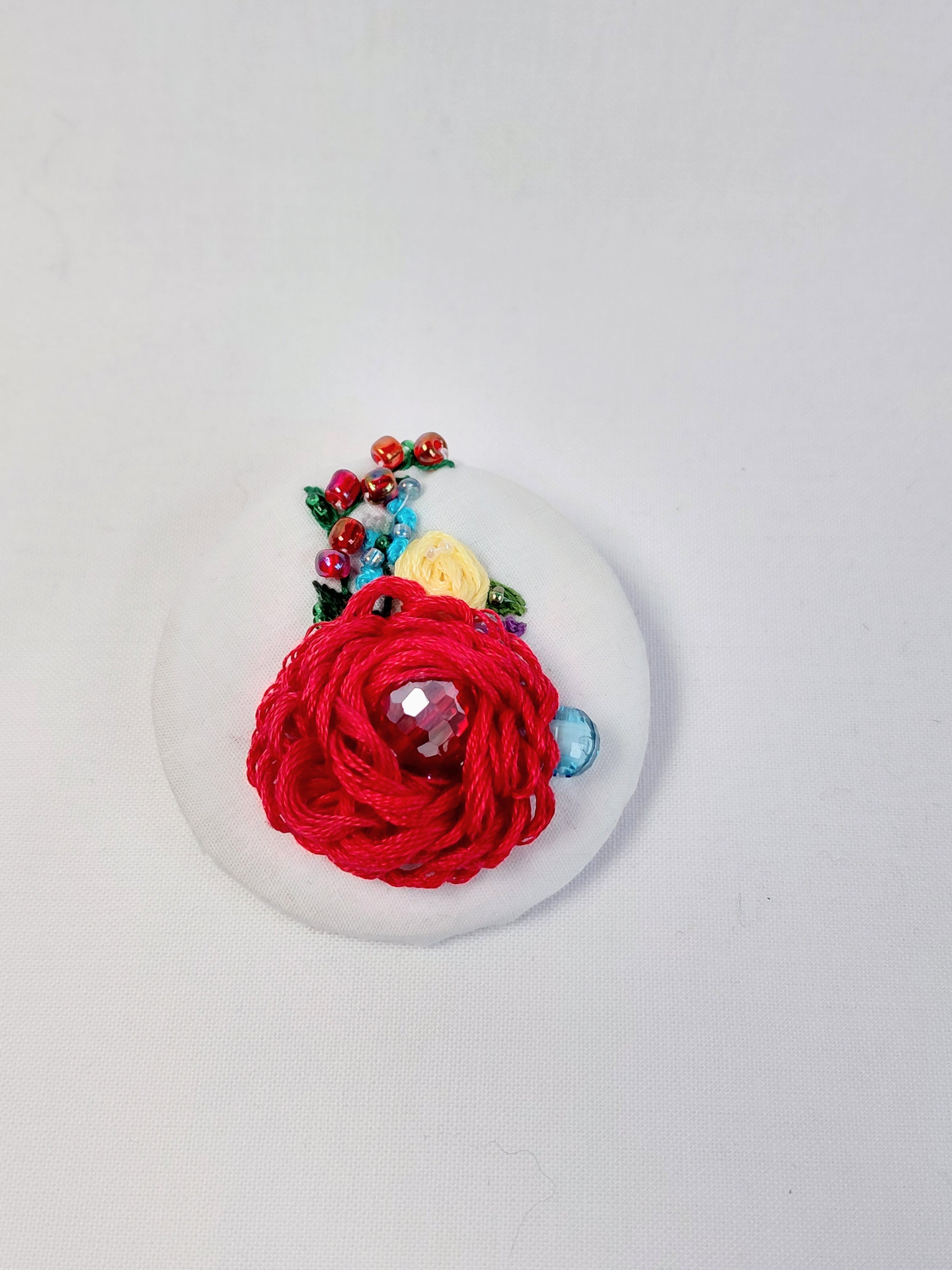 Decorative red flower brooch on white background