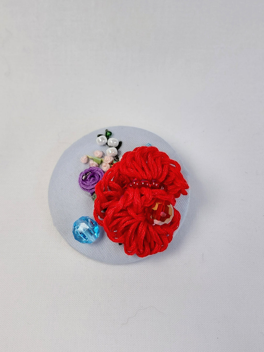 Decorative red flower brooch on light blue background