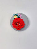 Decorative red flower brooch on grey background