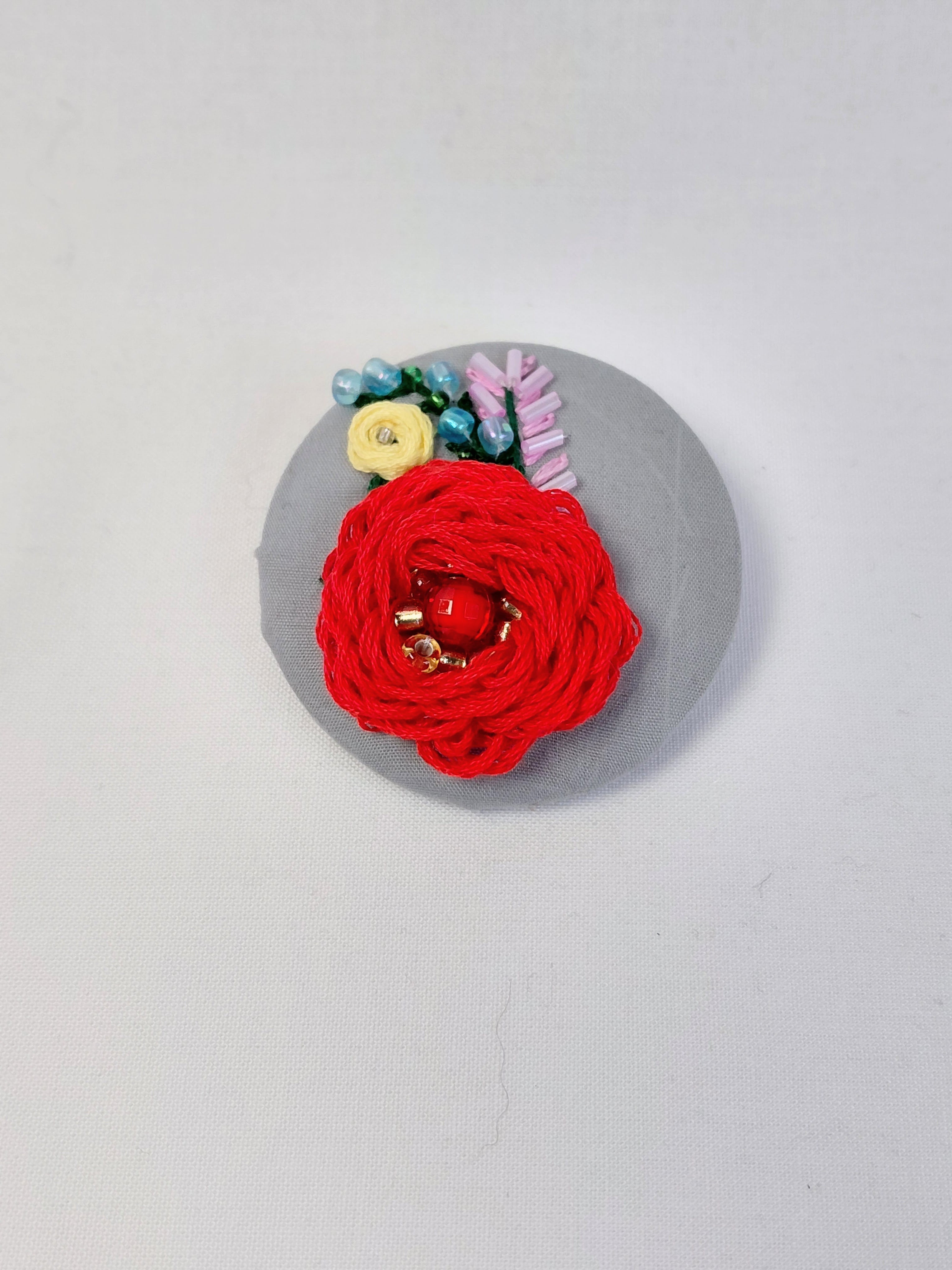 Decorative red flower brooch on grey background