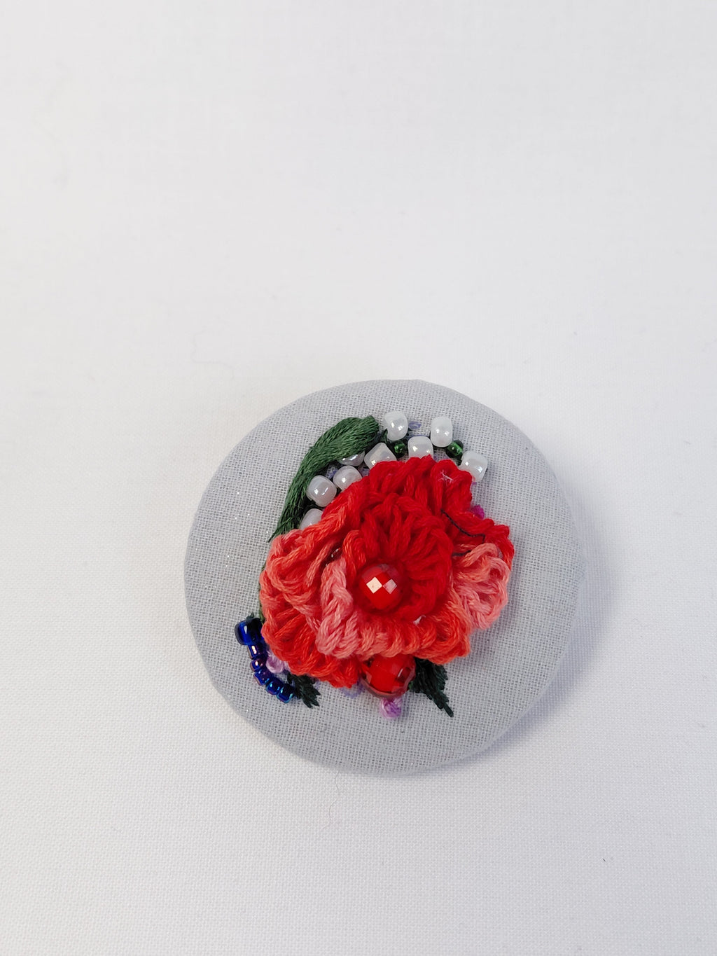 Decorative red flower brooch on light blue with specs background