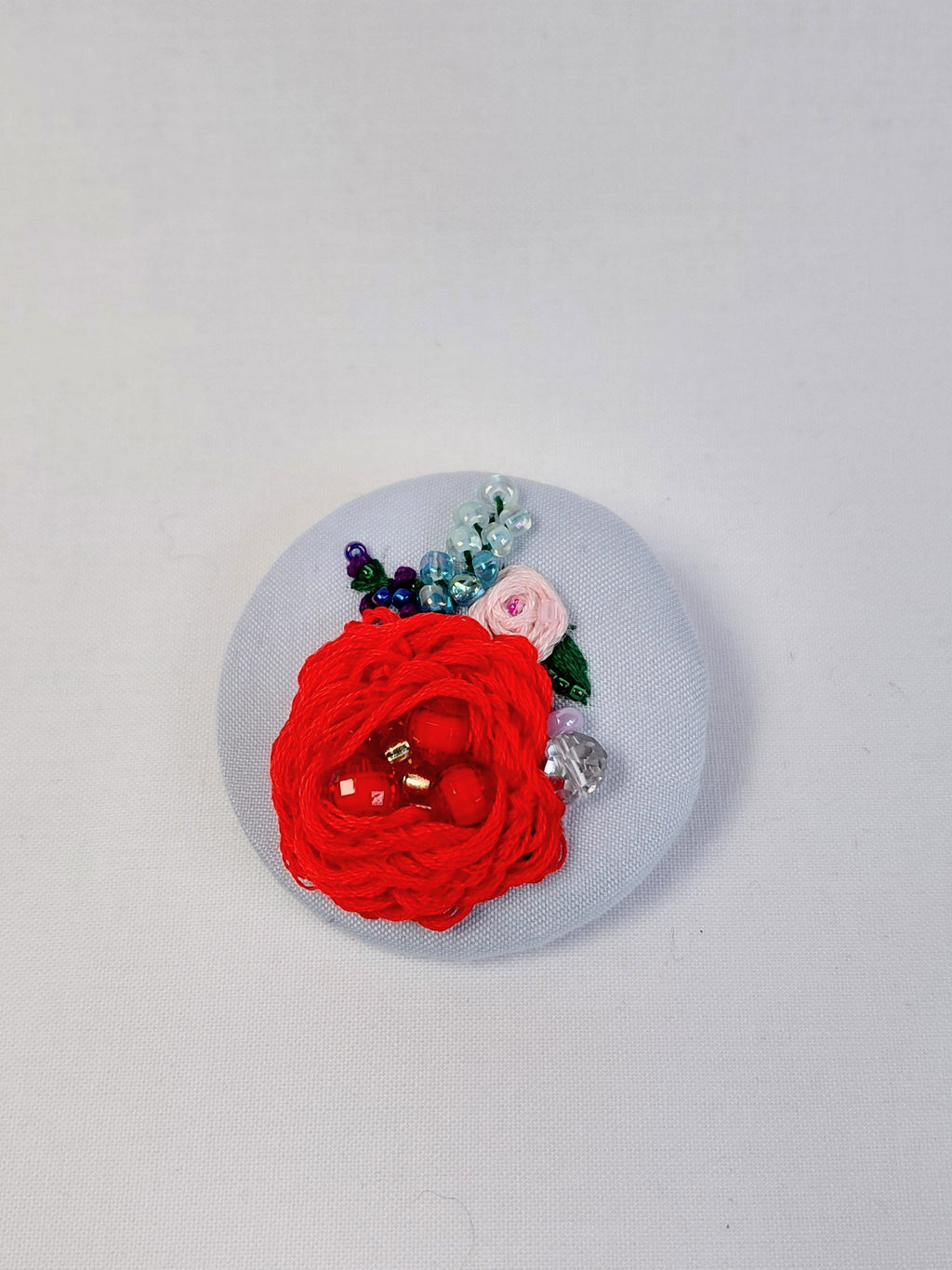 Decorative red flower brooch on light blue background