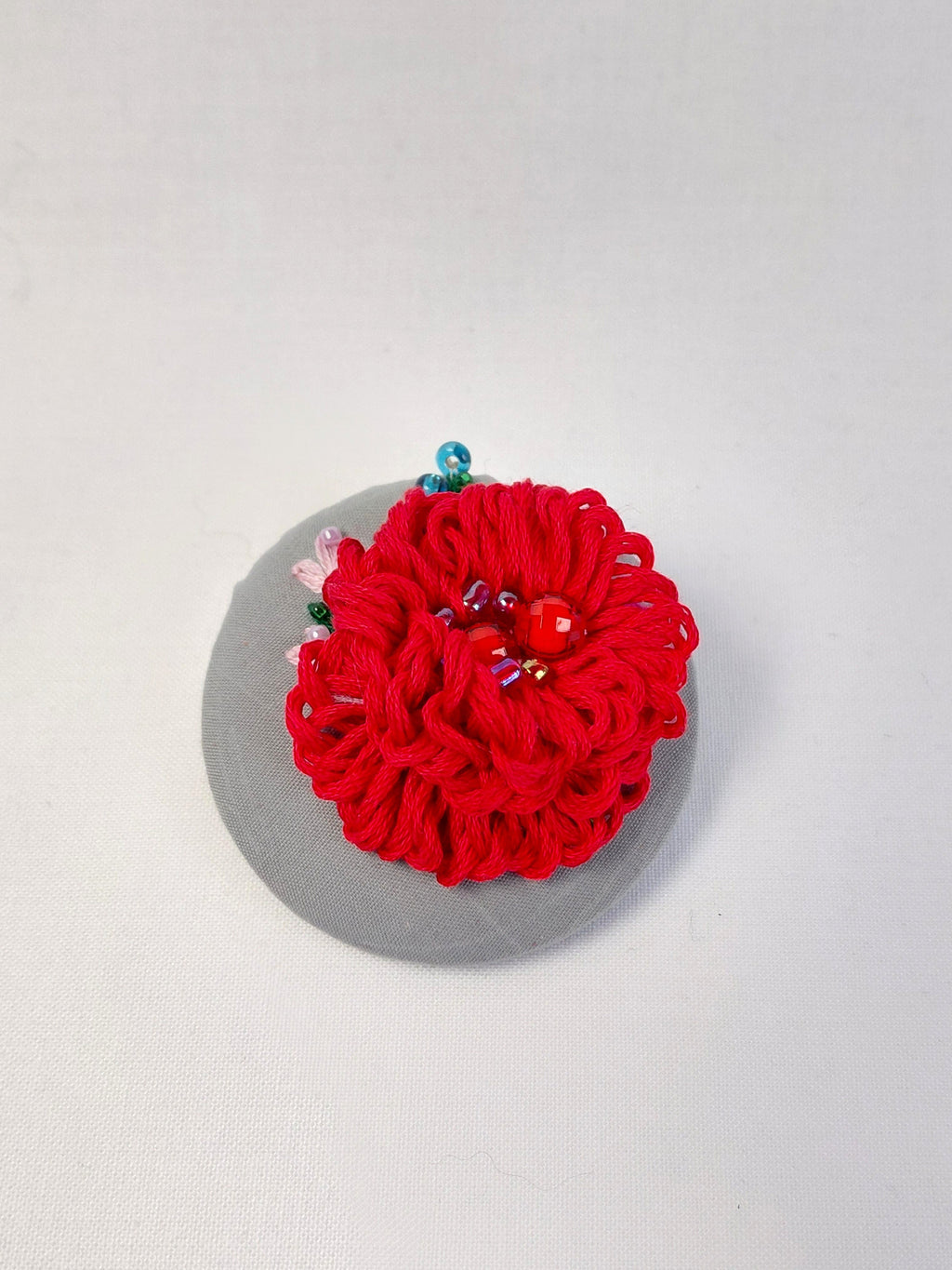 Decorative red flower brooch on grey background