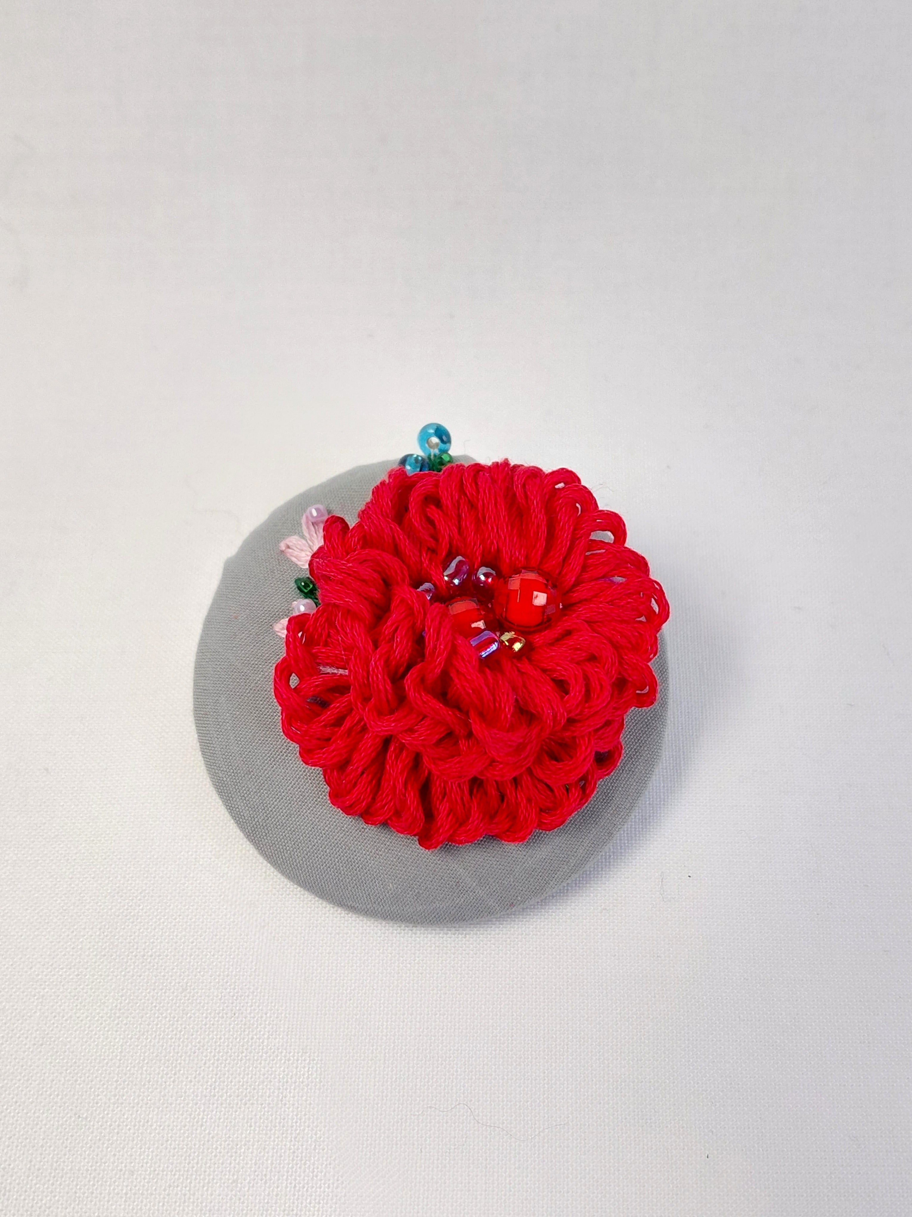 Decorative red flower brooch on grey background