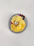 Decorative yellow flower brooch on grey background