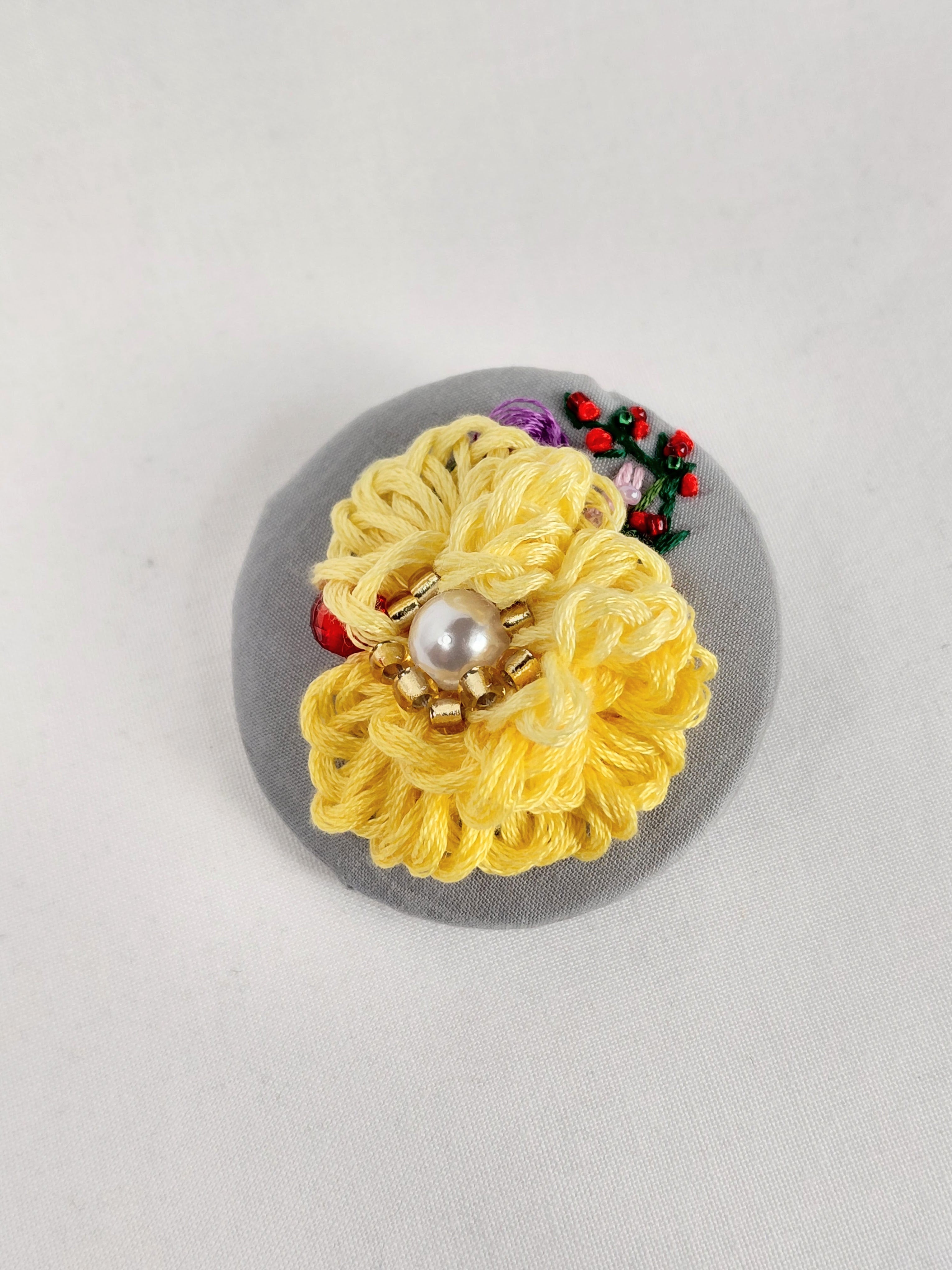 Decorative yellow flower brooch on grey background