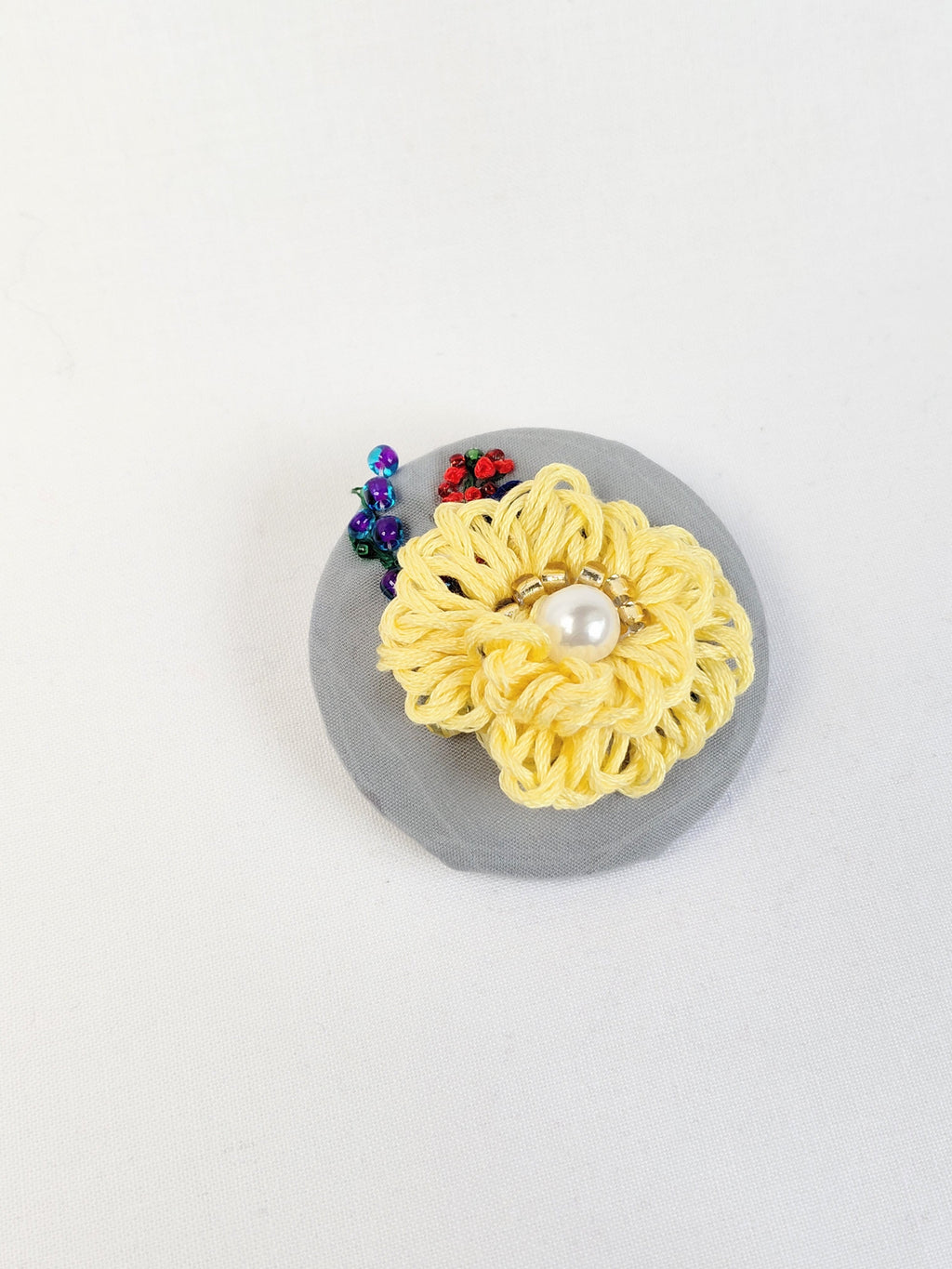 Decorative yellow flower brooch on grey background