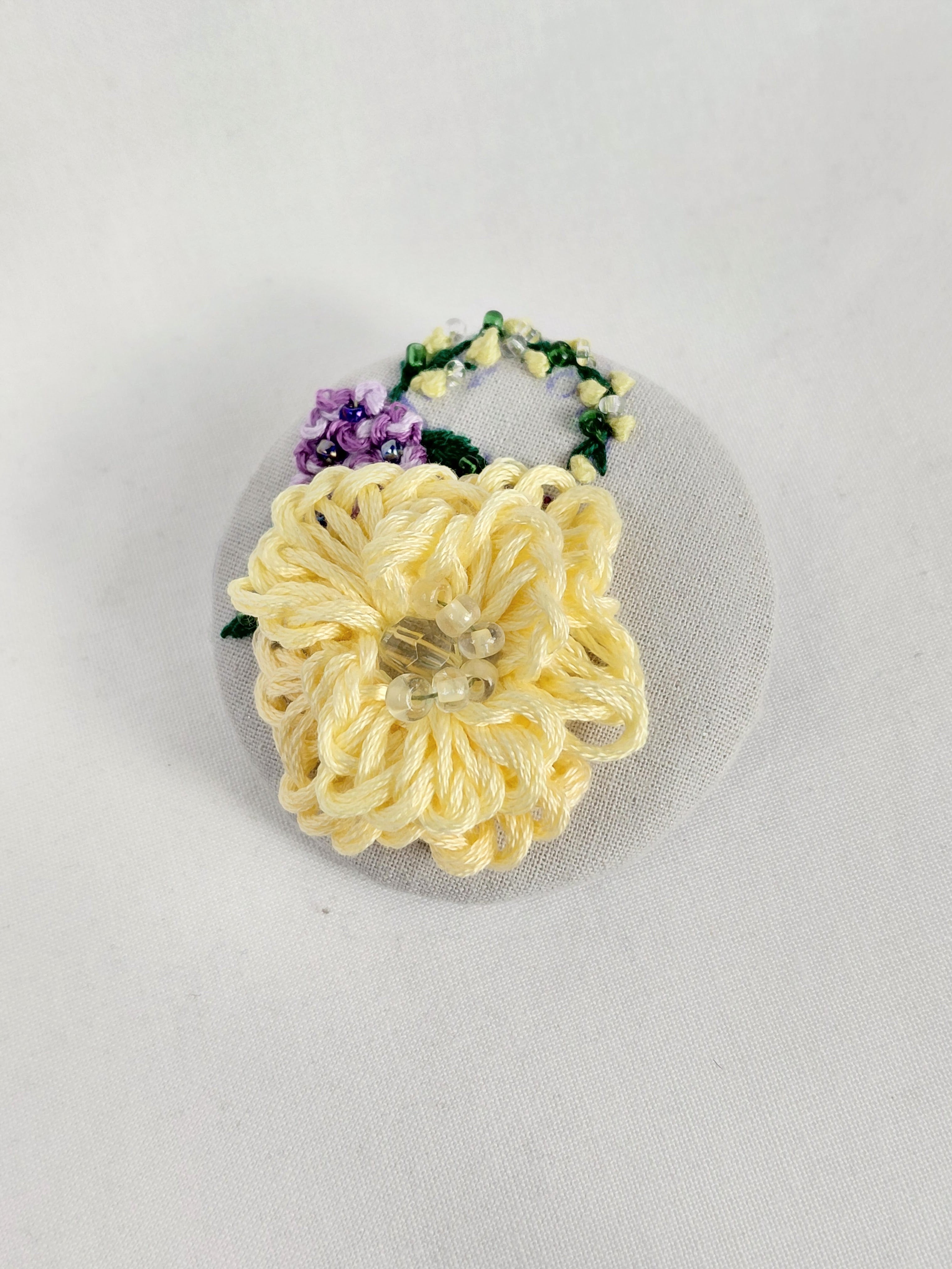 Decorative yellow flower brooch on grey with specs background