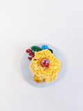 Decorative yellow flower brooch on light blue background