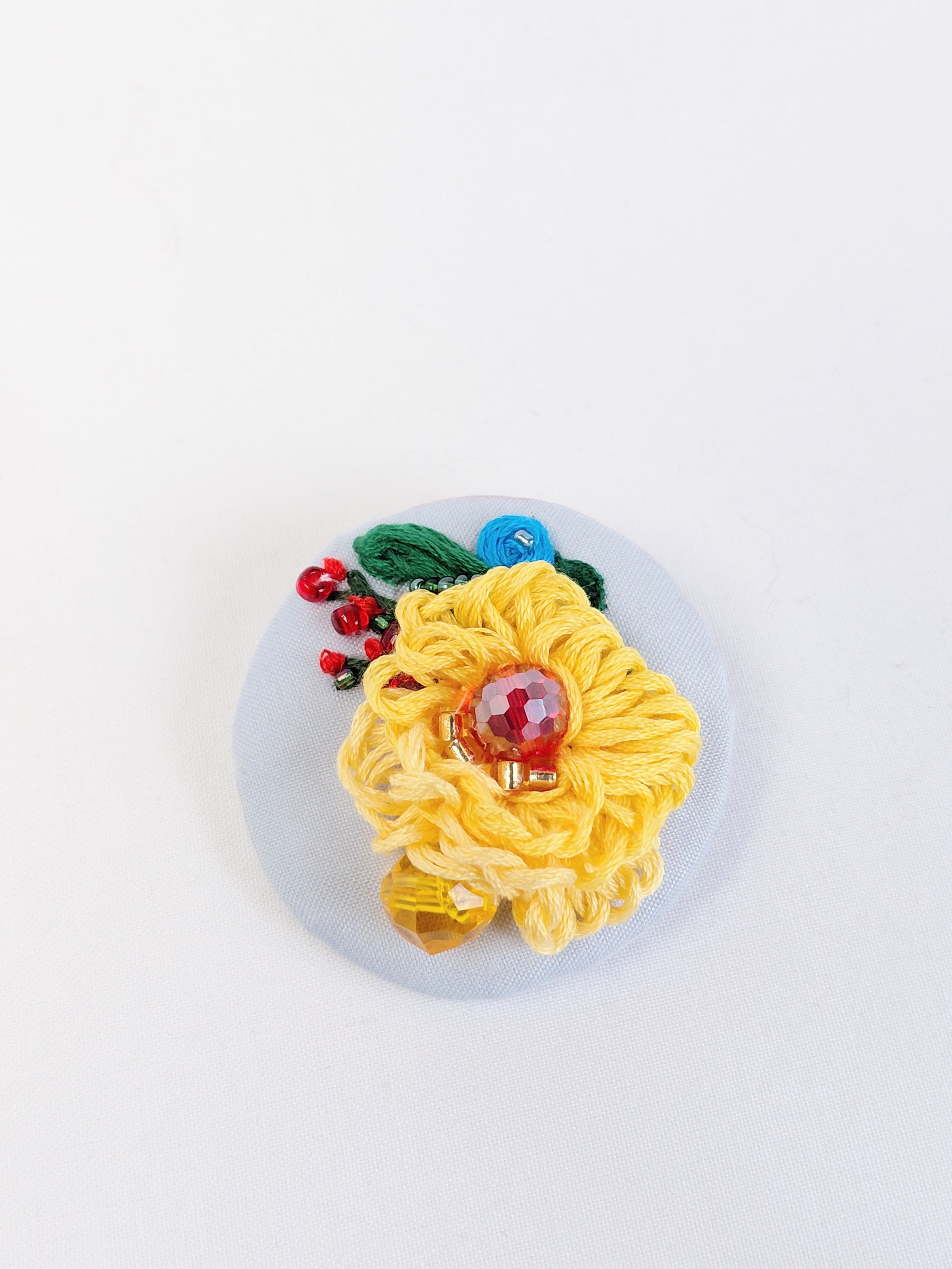 Decorative yellow flower brooch on light blue background