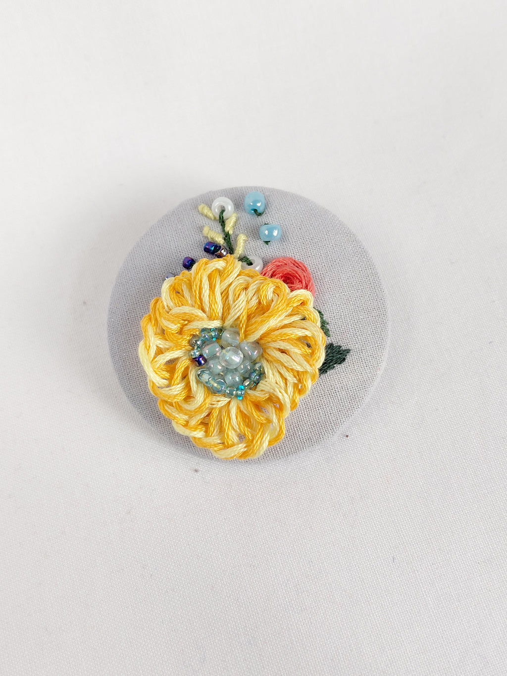 Decorative yellow flower brooch on grey with specs background