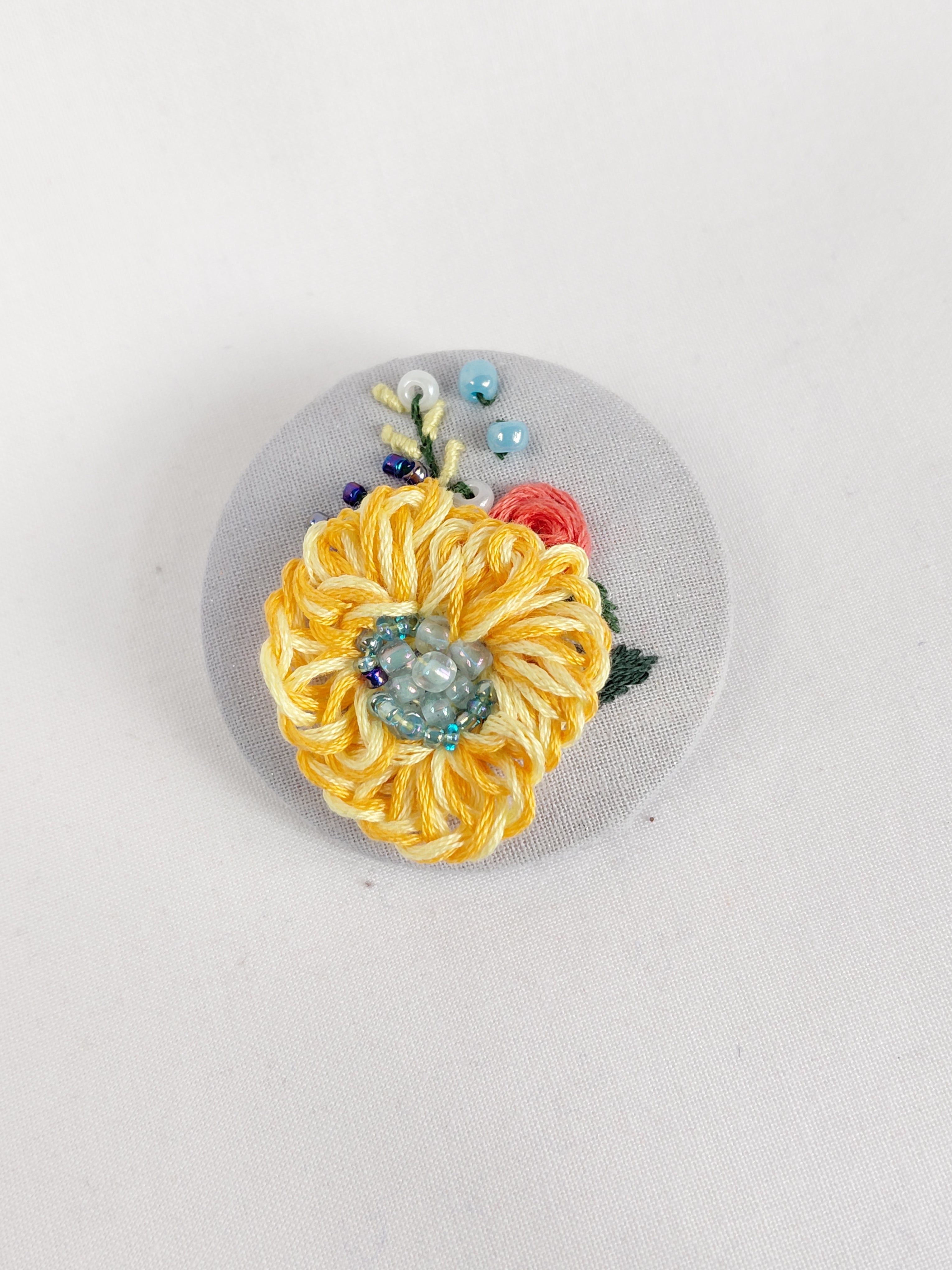 Decorative yellow flower brooch on grey with specs background