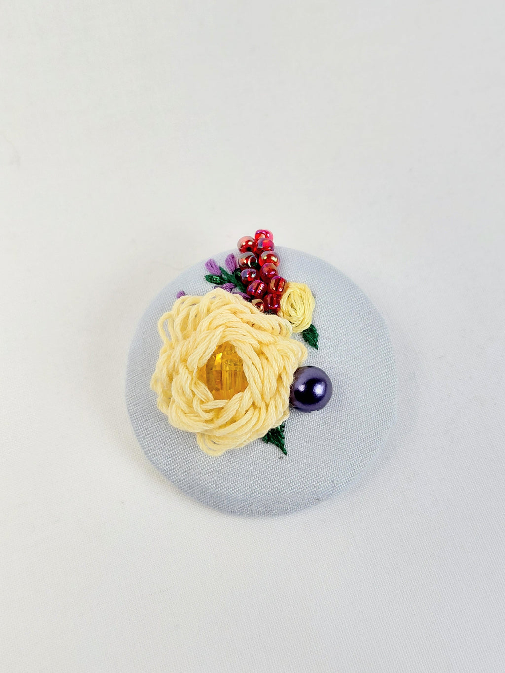 Decorative yellow flower brooch on light blue background