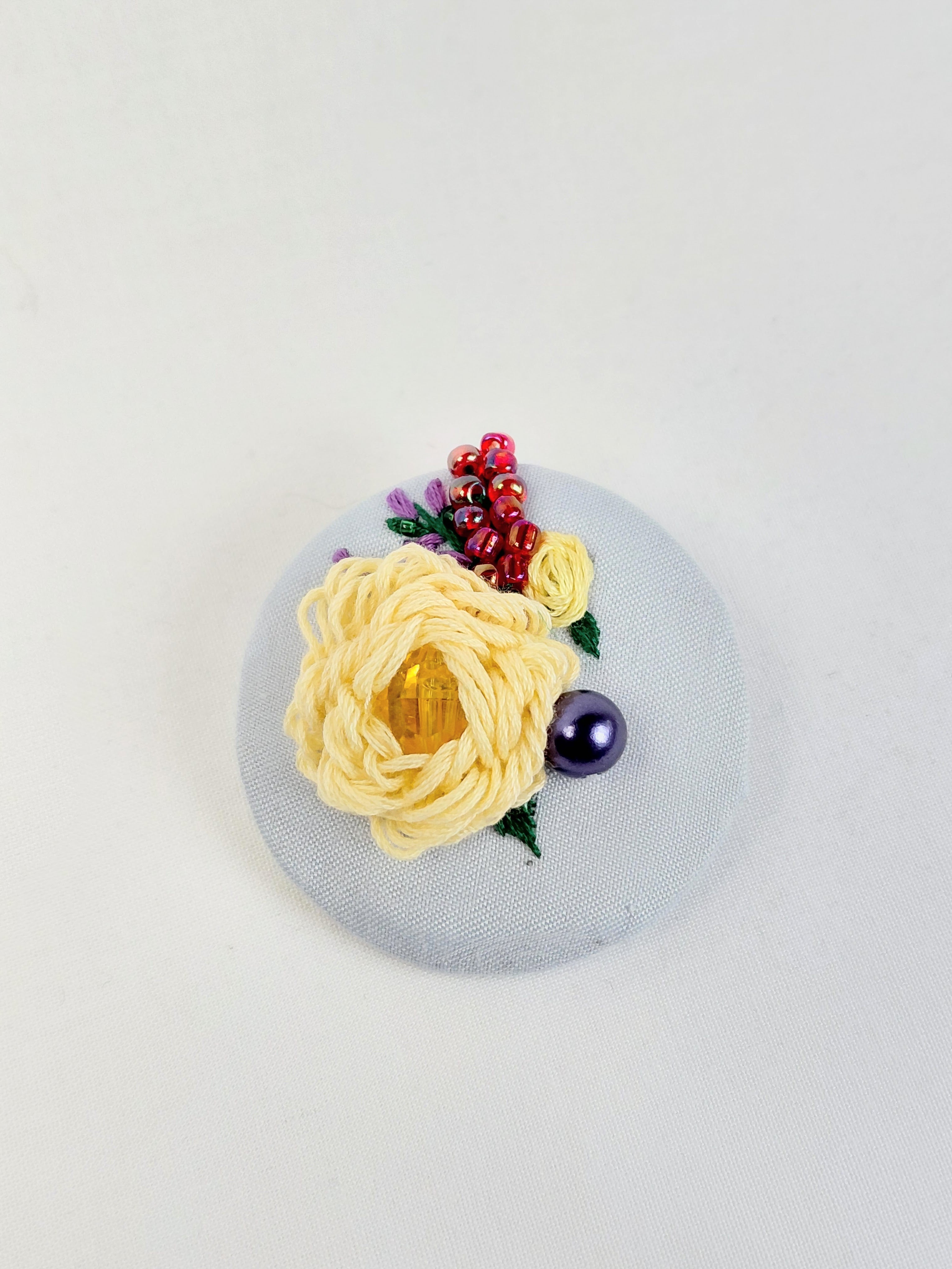 Decorative yellow flower brooch on light blue background