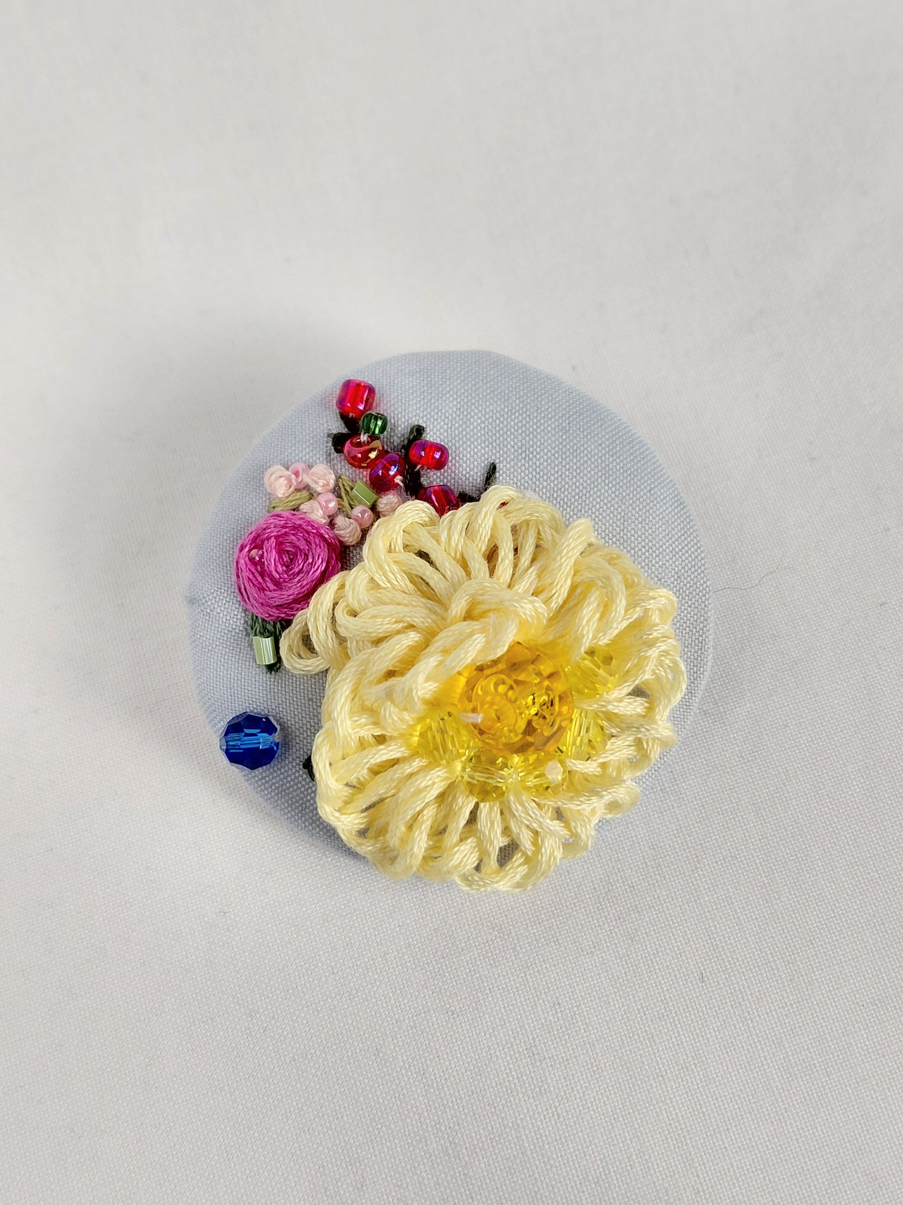 Decorative yellow flower brooch on light blue background