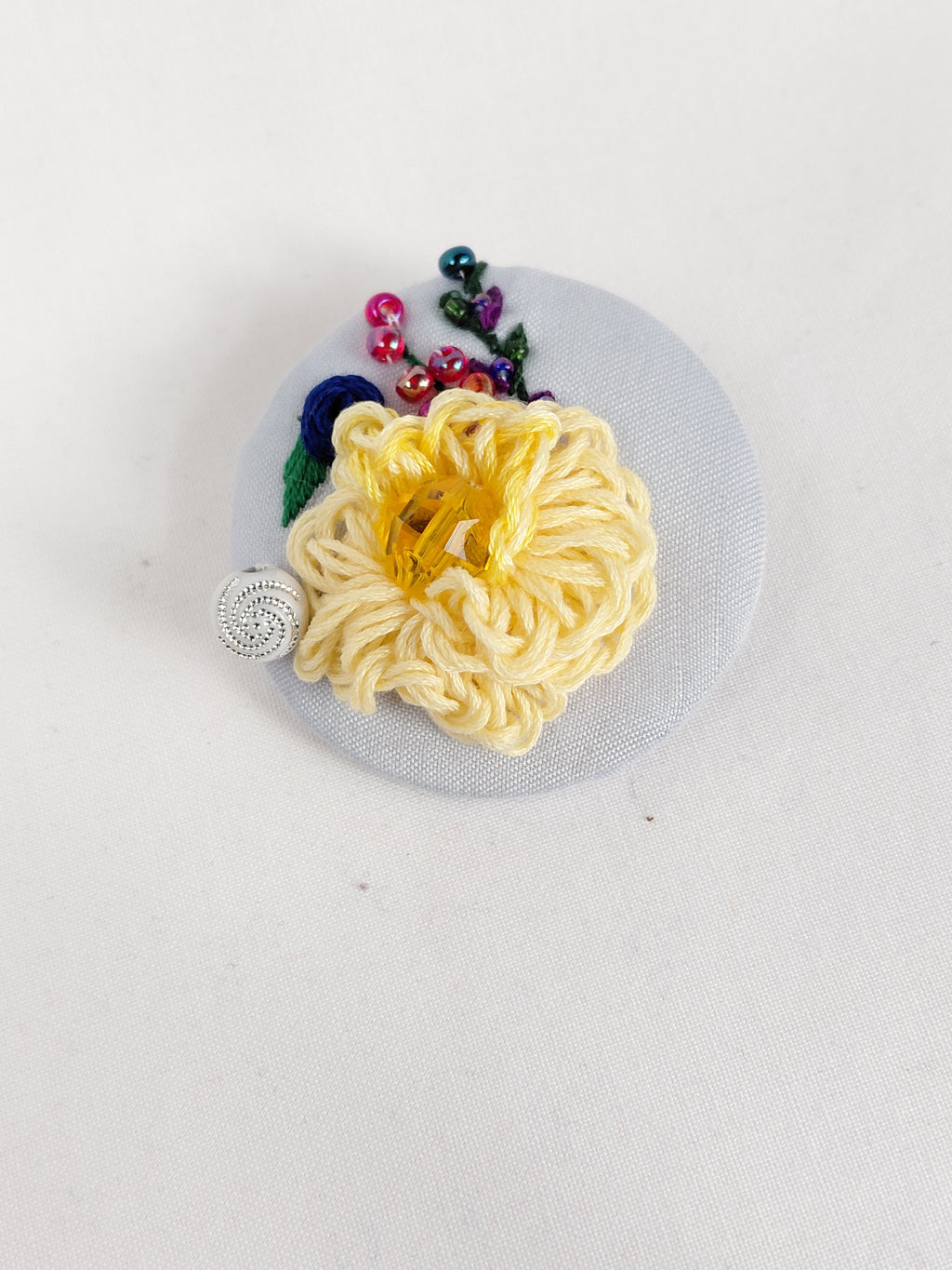 Decorative yellow flower brooch on light blue background