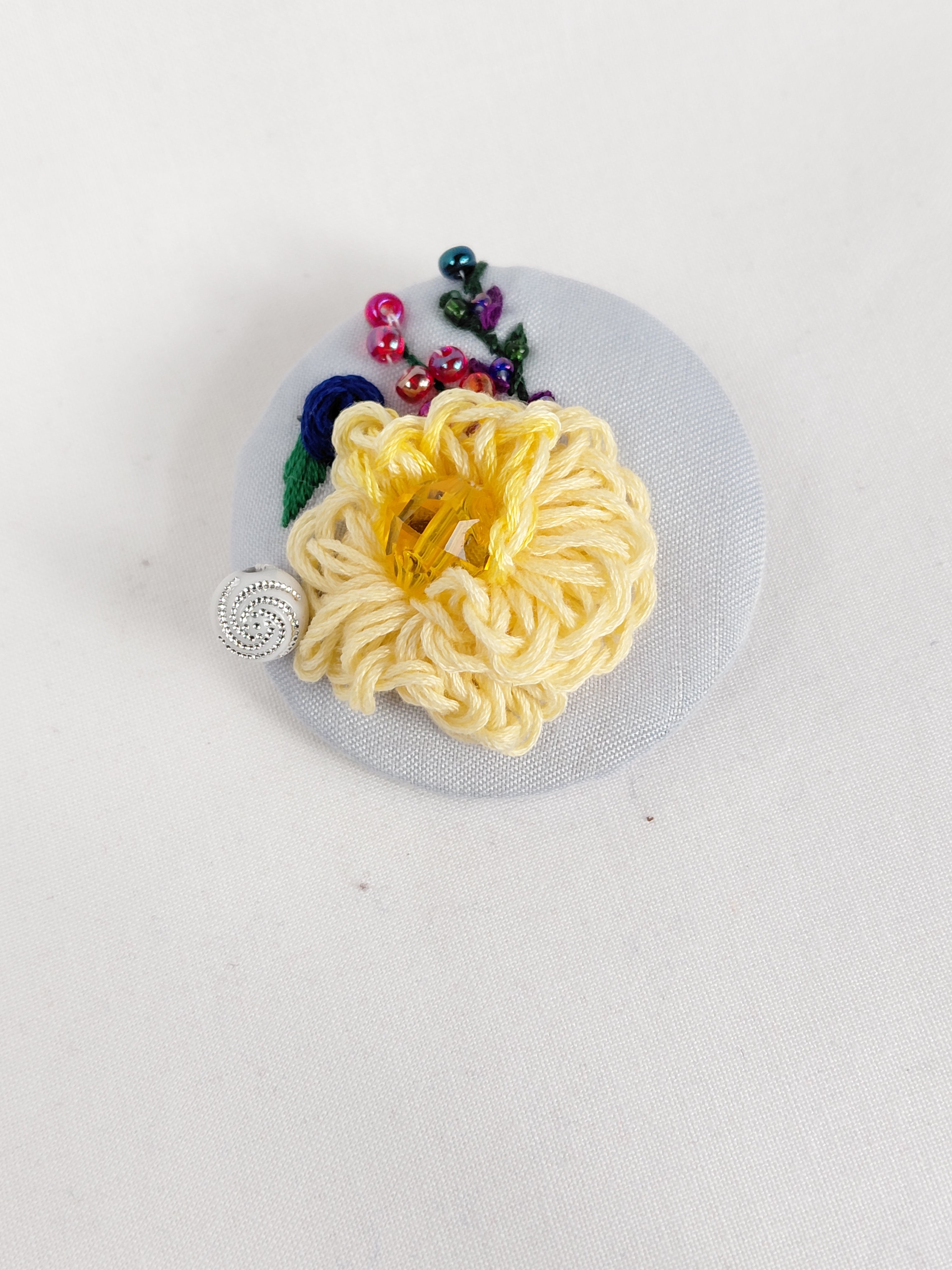 Decorative yellow flower brooch on light blue background