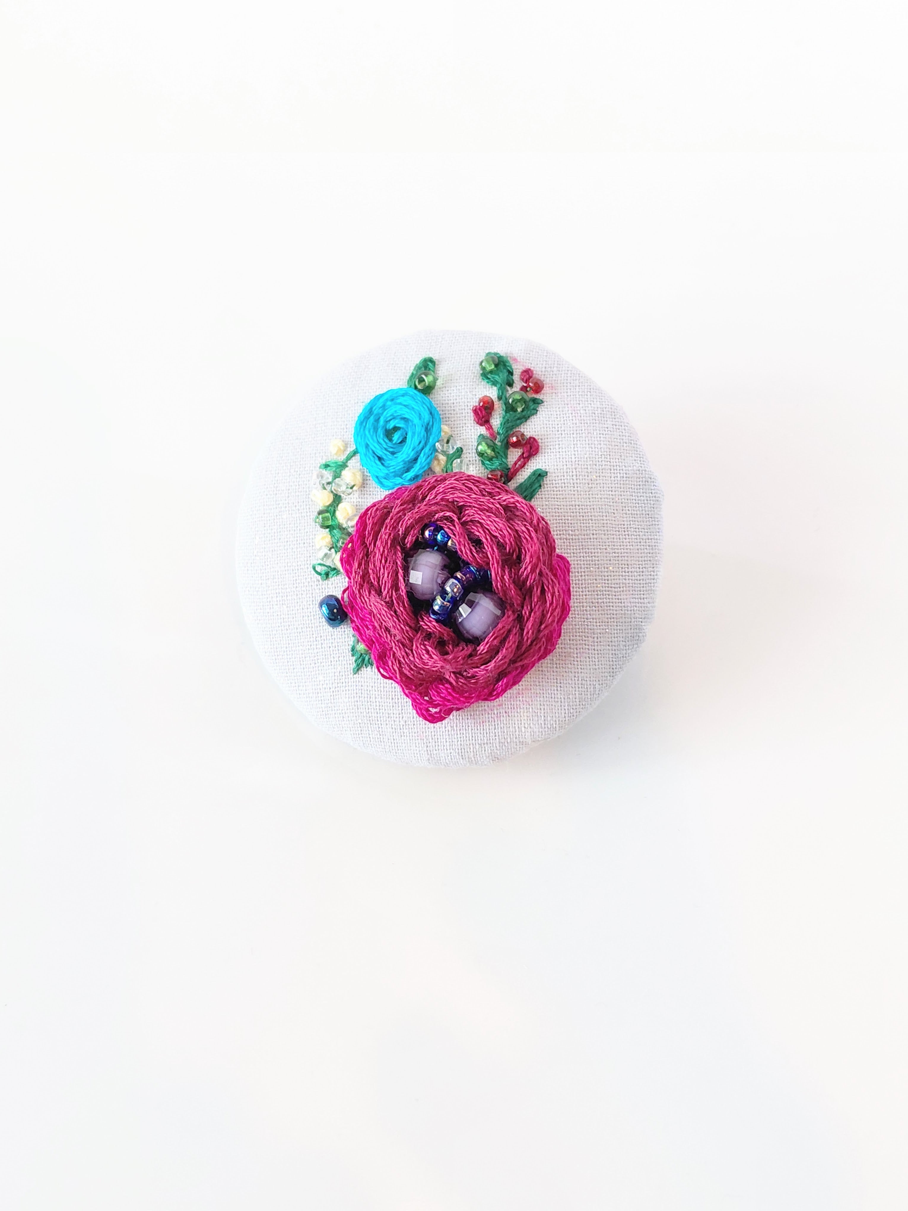 Decorative burgundy flower brooch on grey background