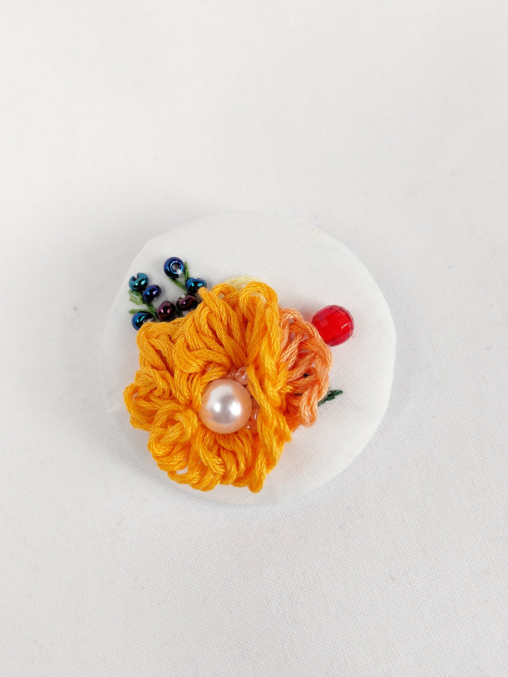 Decorative orange flower brooch on white background