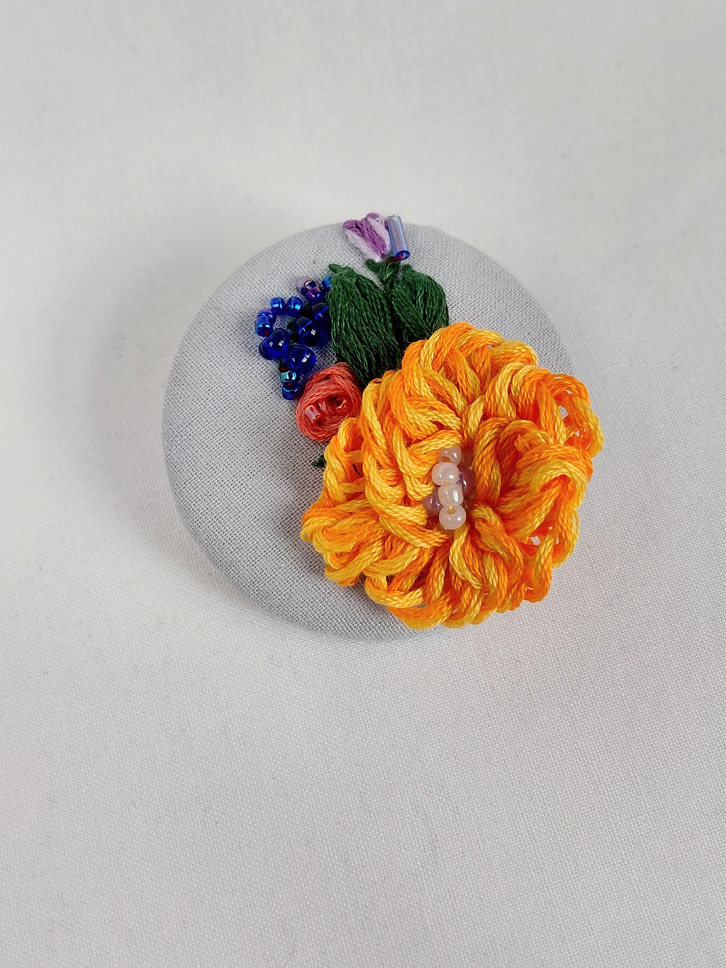 Decorative orange flower brooch on light blue with specs background