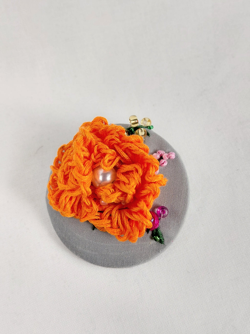 Decorative orange flower brooch on grey background