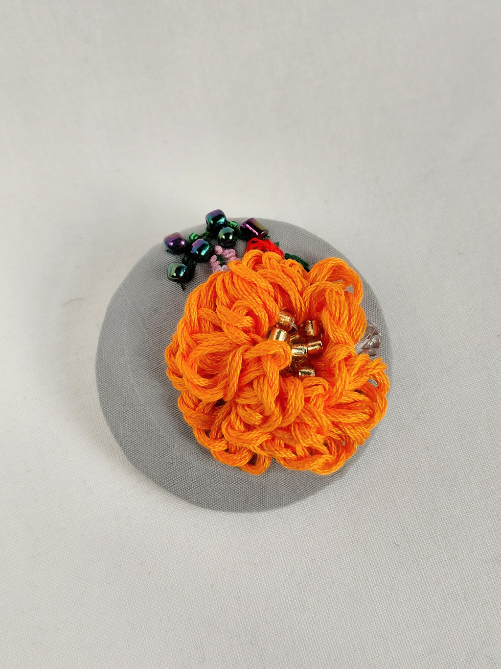 Decorative orange flower brooch on grey background