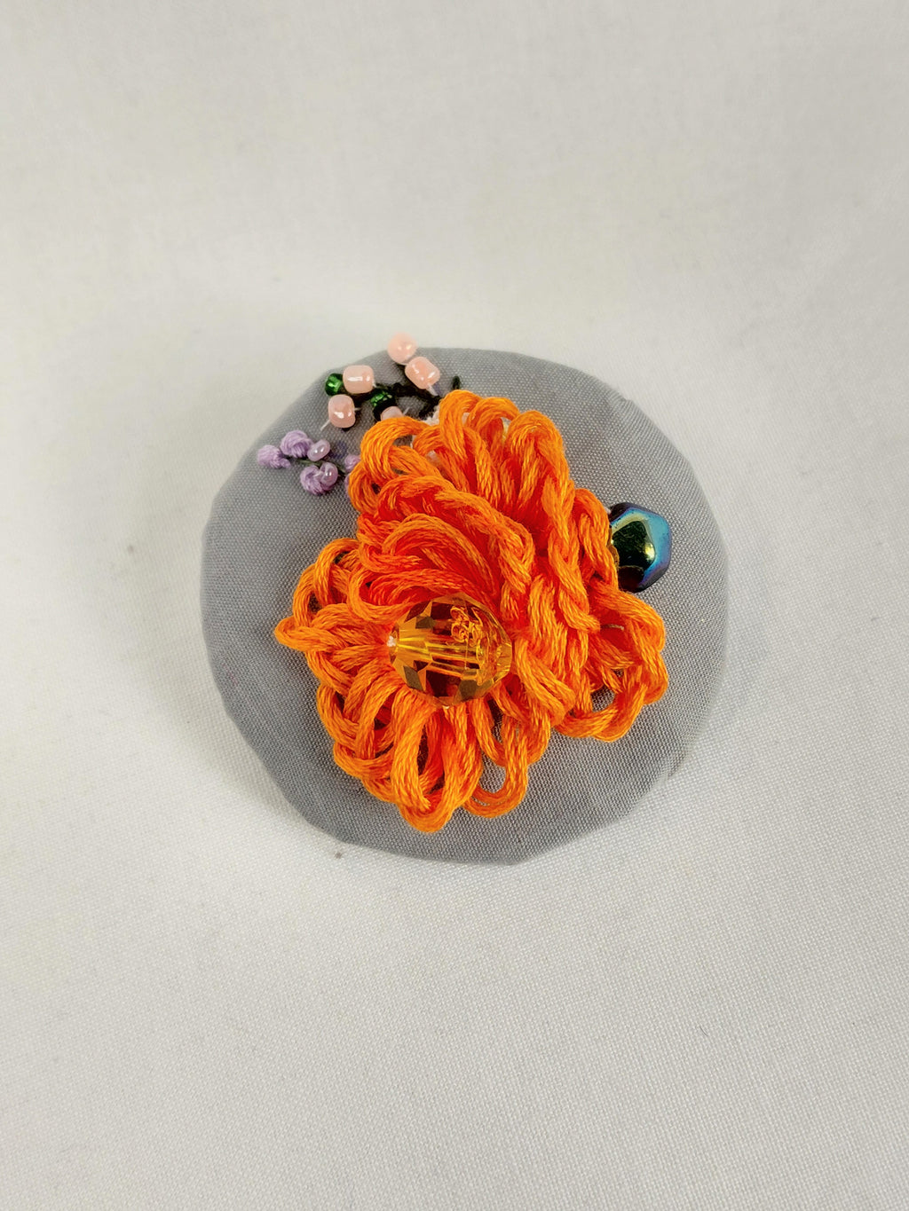 Decorative orange flower brooch on grey background