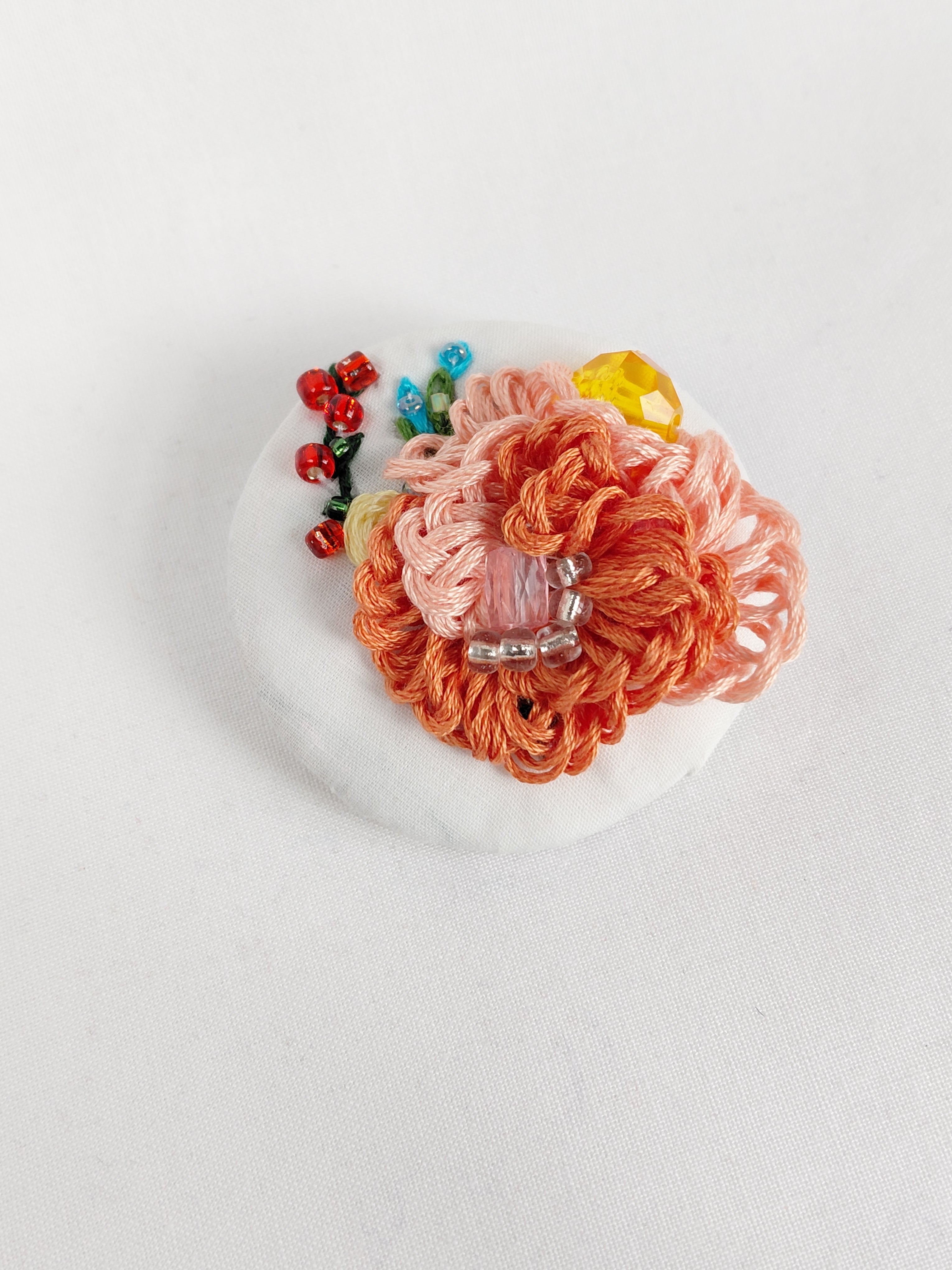 Decorative orange flower brooch on white background