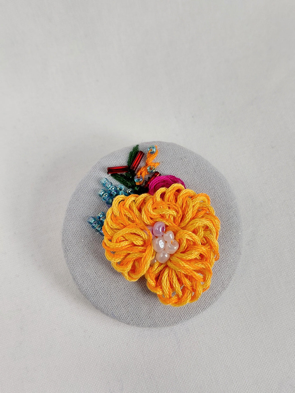 Decorative orange flower brooch on grey with specs background