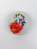 Decorative orange flower brooch on grey with specs background