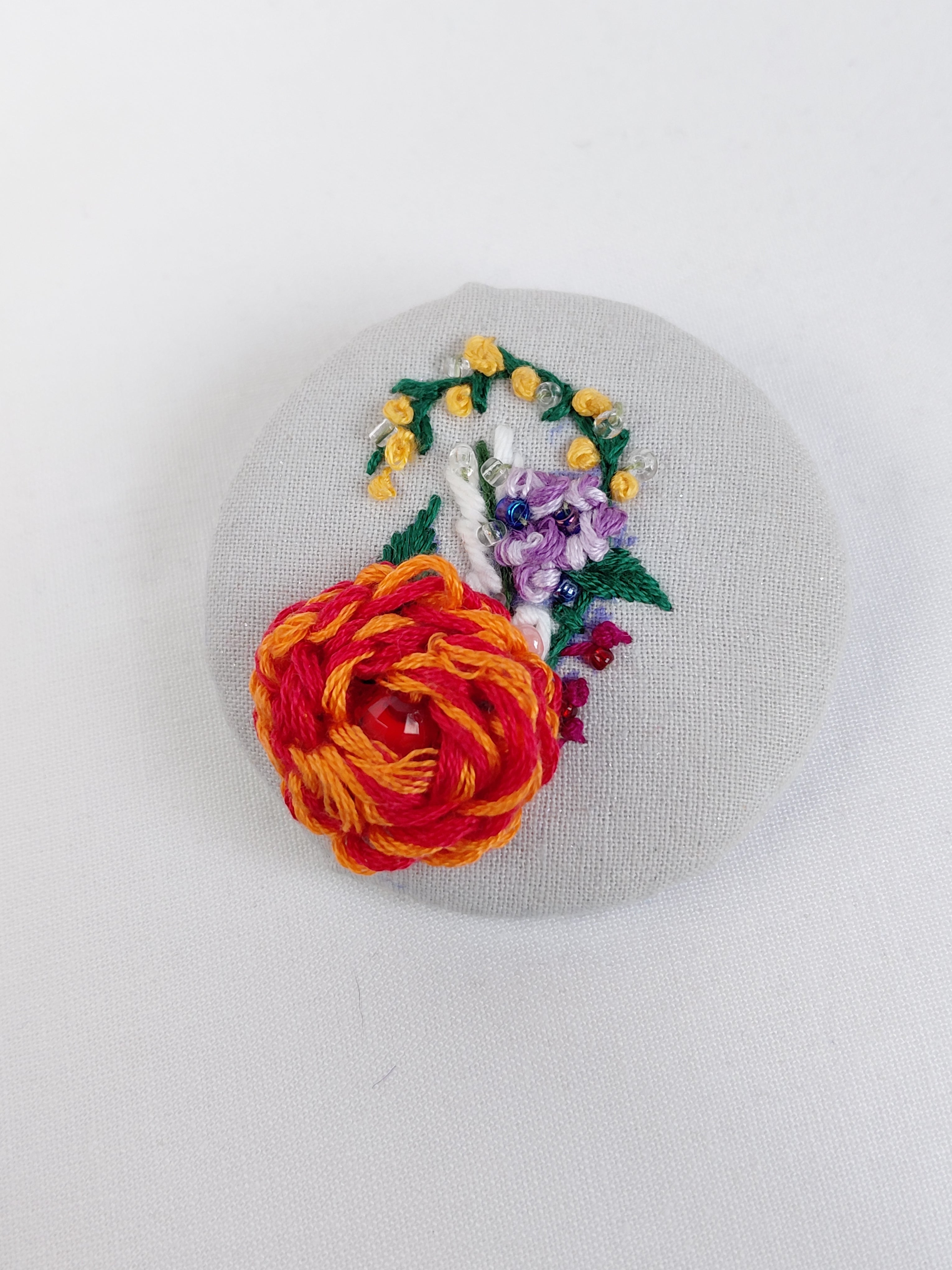 Decorative orange flower brooch on grey with specs background