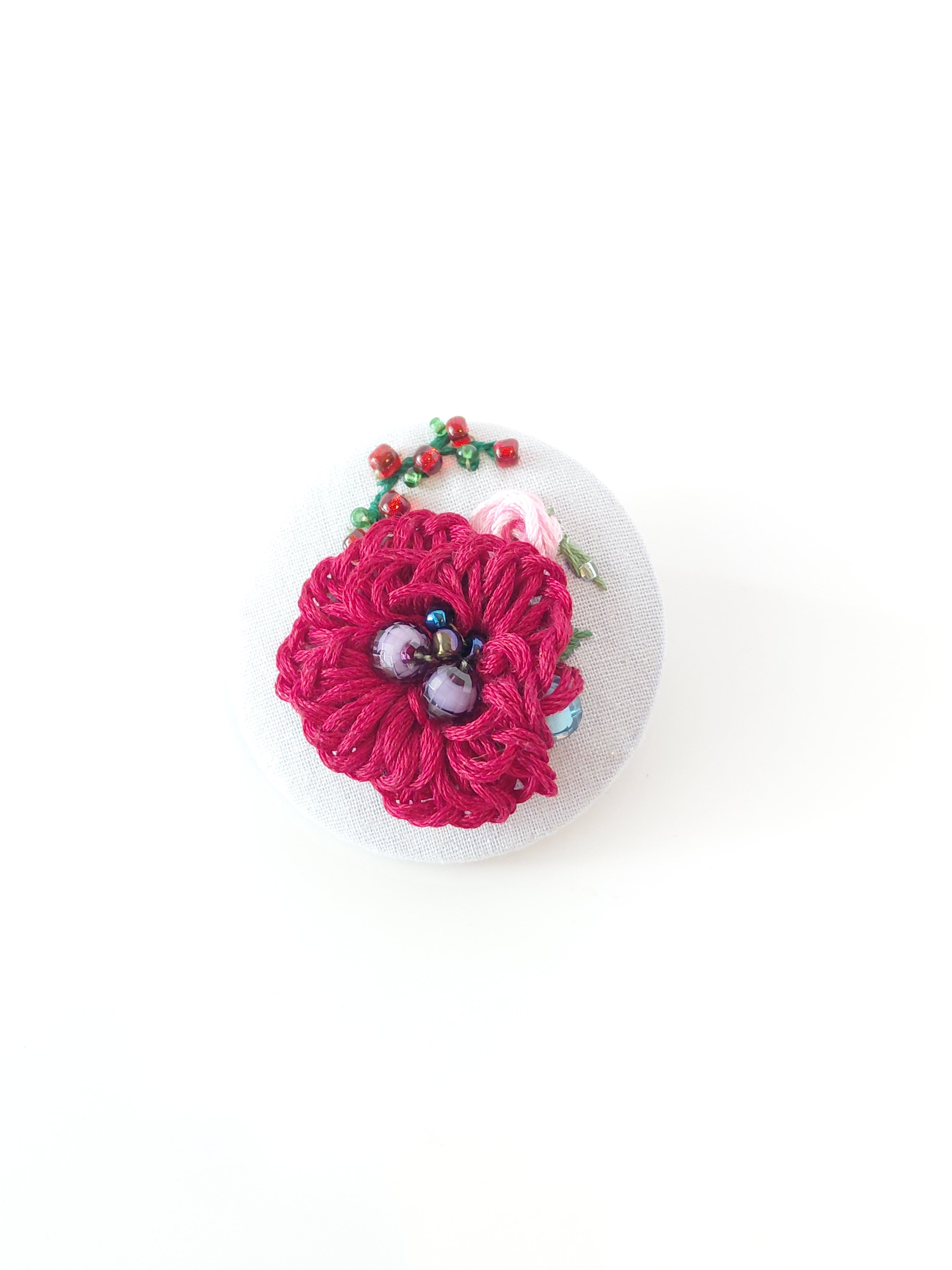 Decorative burgundy flower brooch on grey background
