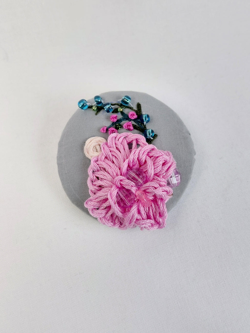Decorative pink flower brooch on grey background