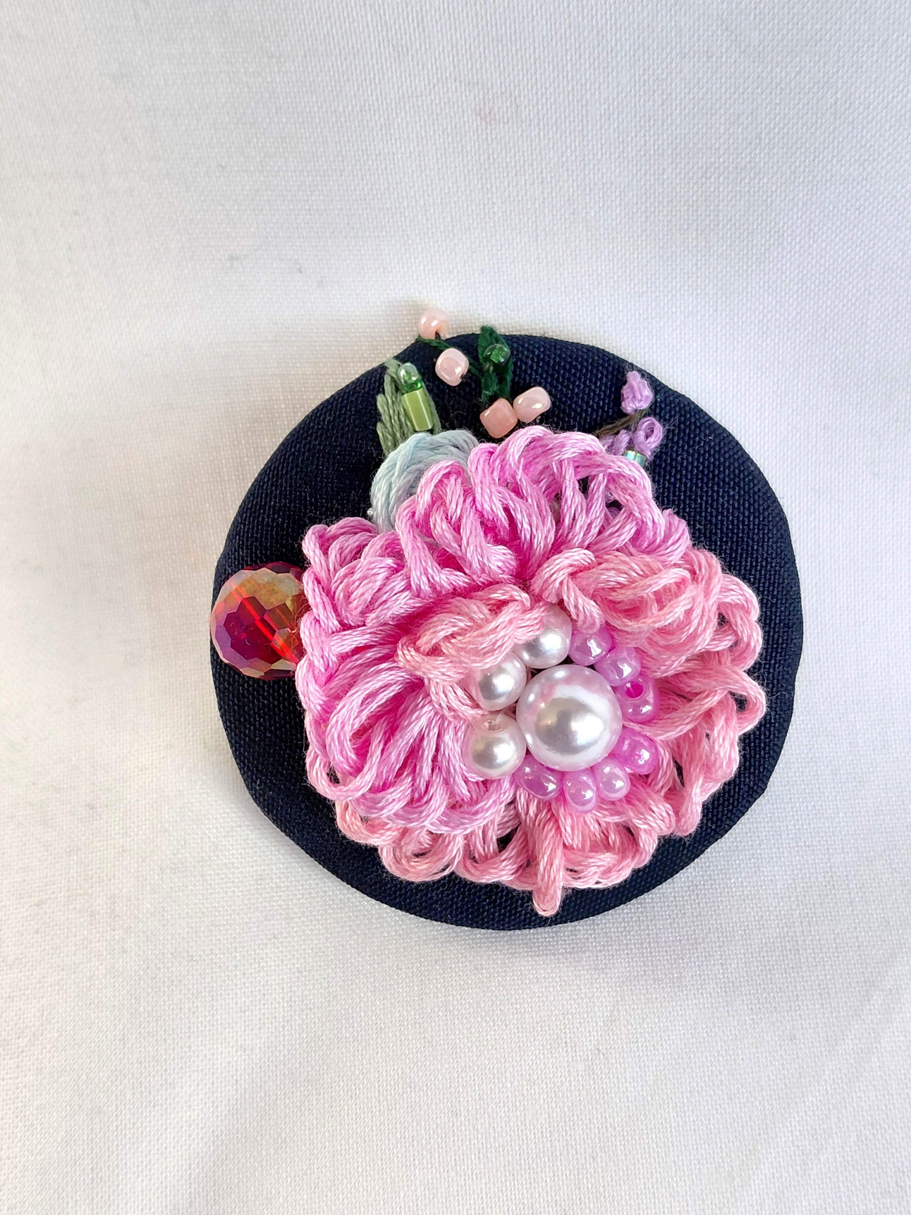 Decorative pink flower brooch on black background