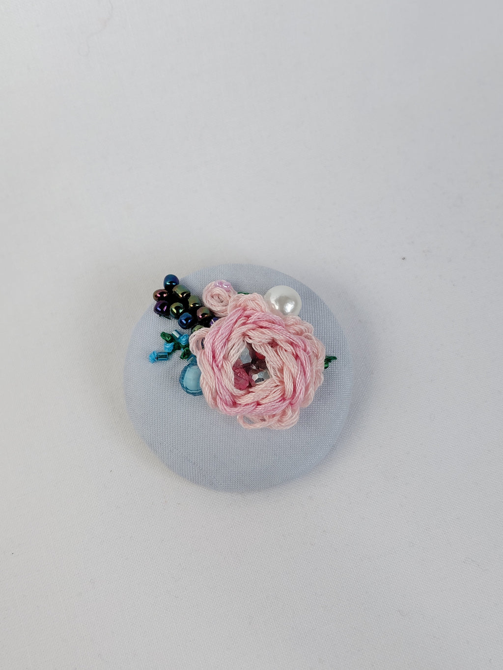 Decorative pink flower brooch on light blue background