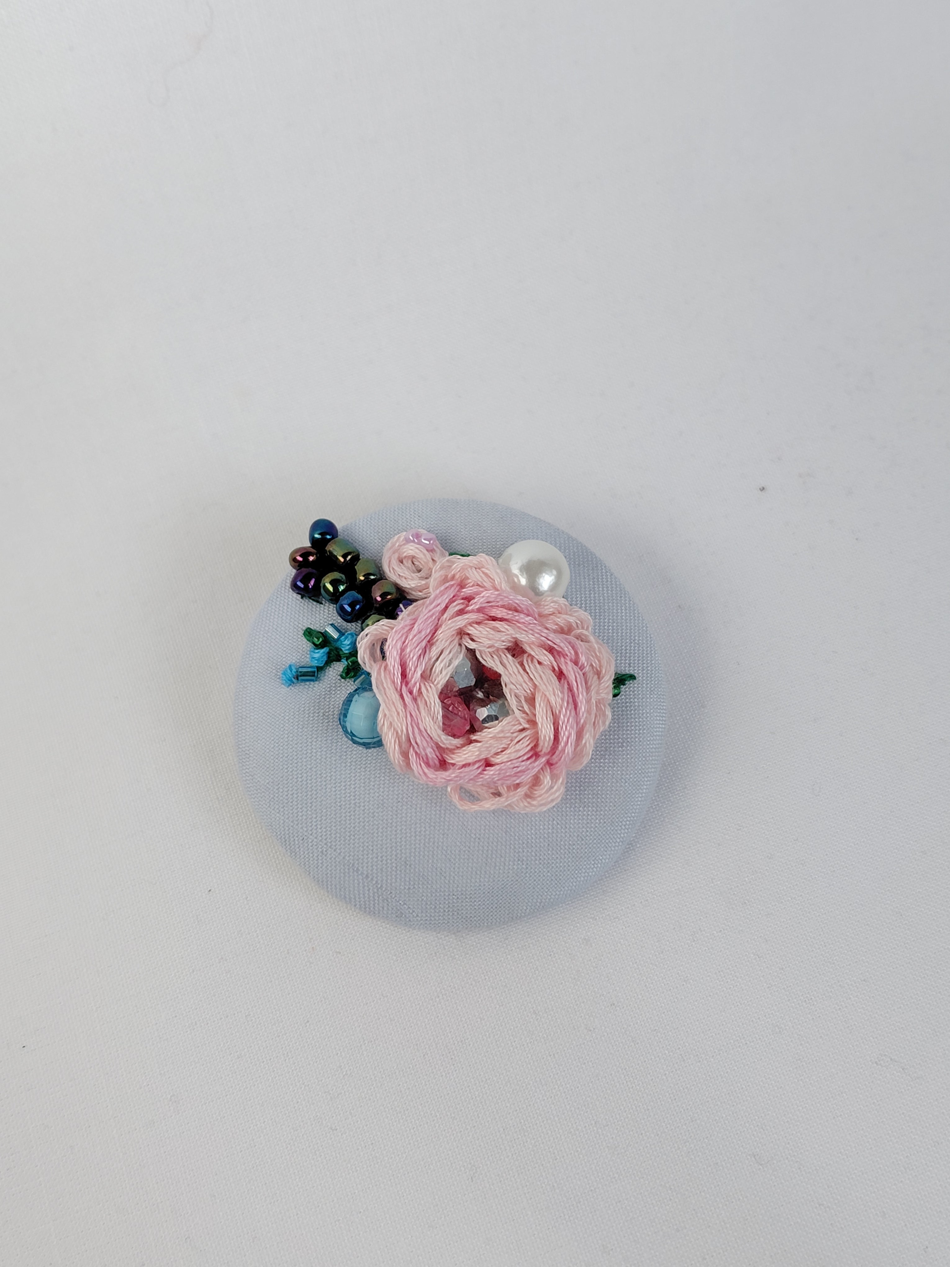Decorative pink flower brooch on light blue background