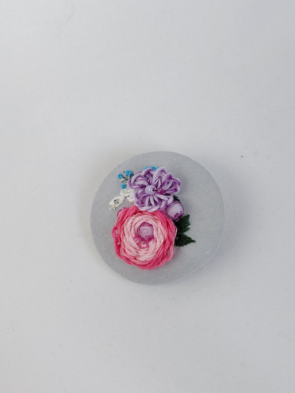 Decorative pink flower brooch on light blue background