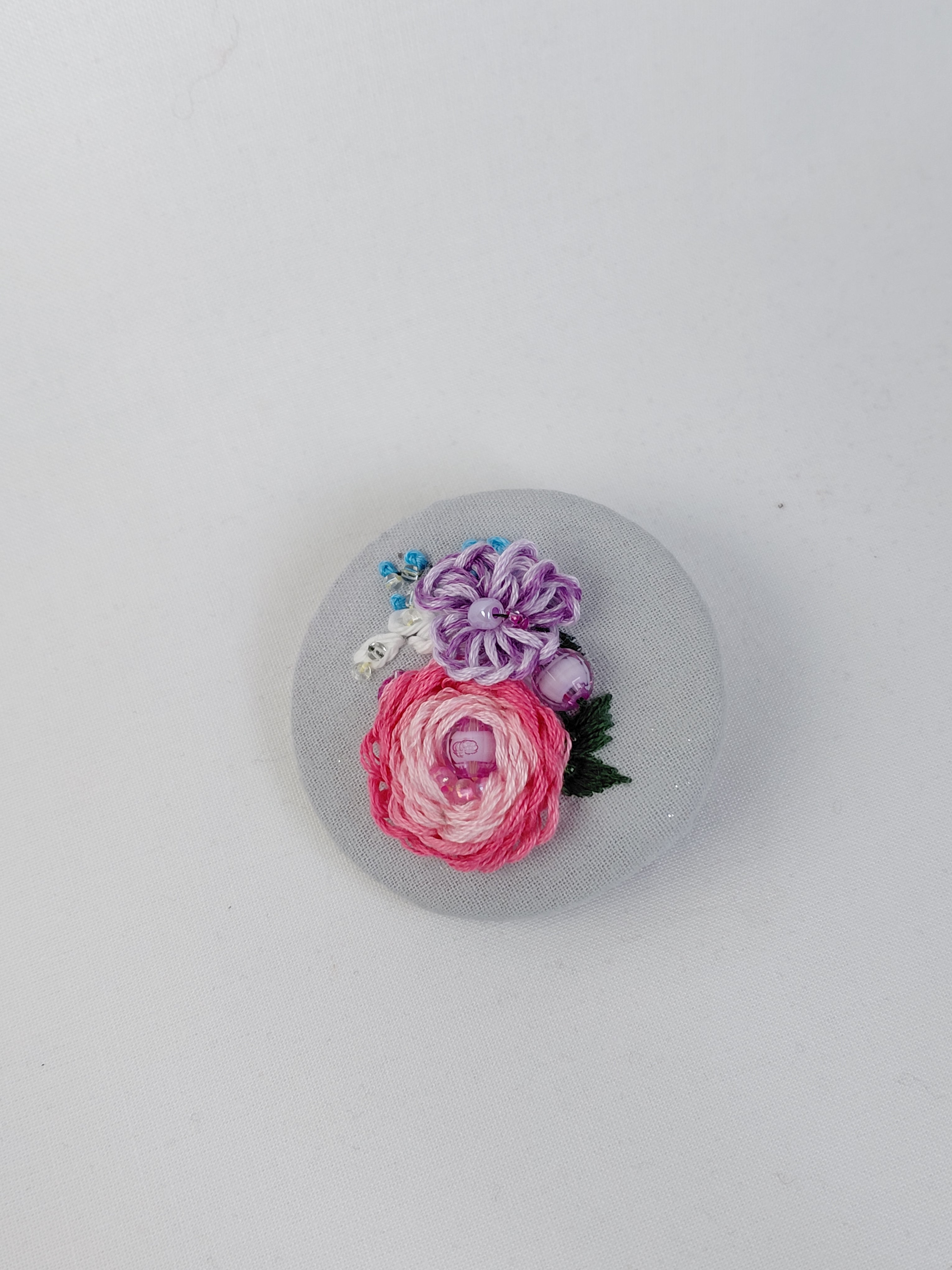 Decorative pink flower brooch on light blue background