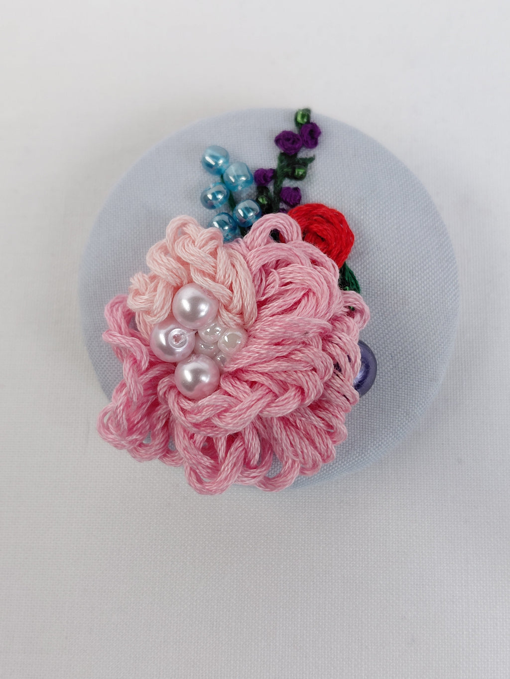 Decorative pink flower brooch on light blue background