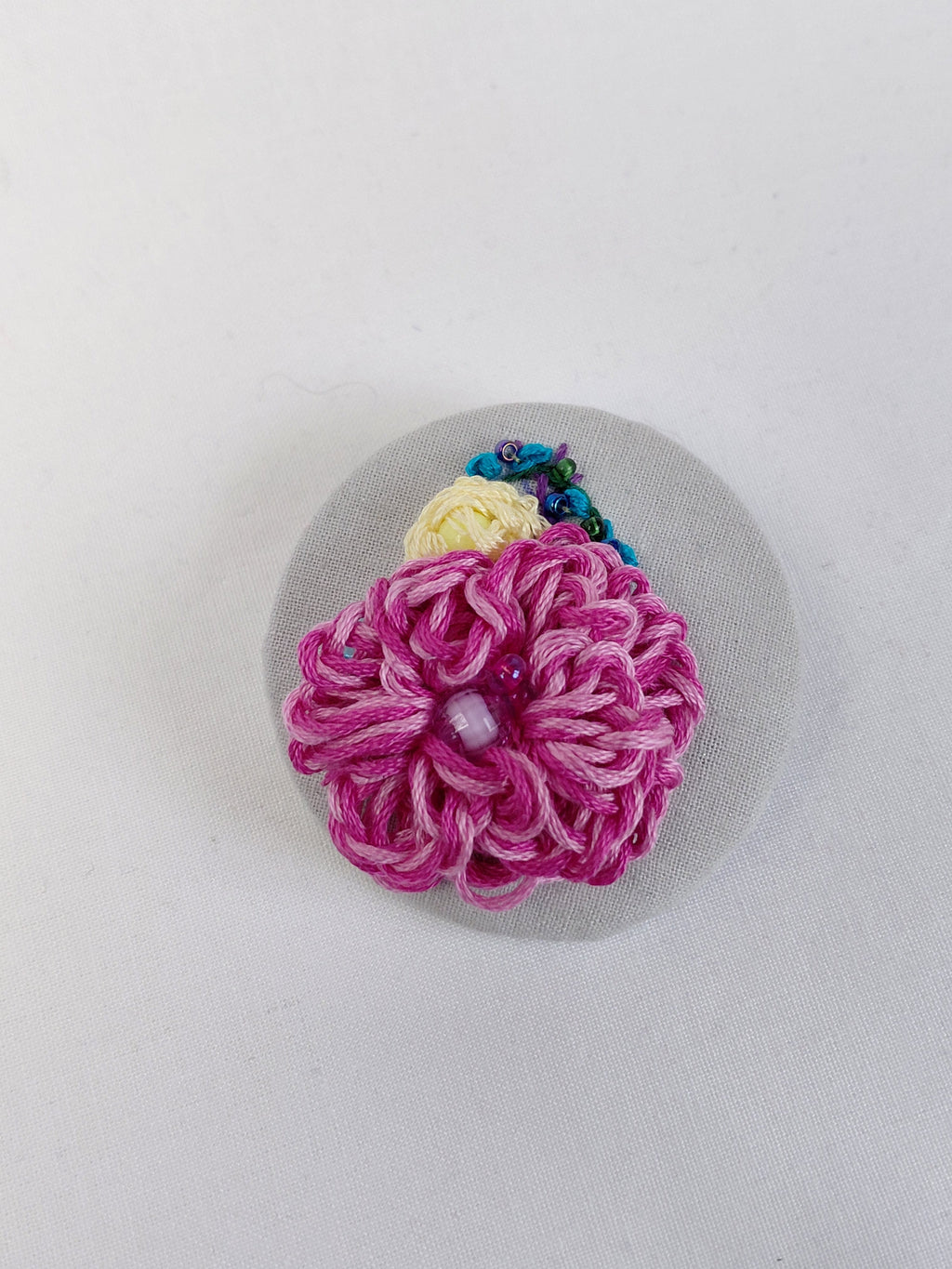Decorative pink flower brooch on grey with specs background
