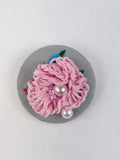 Decorative pink flower brooch on grey background
