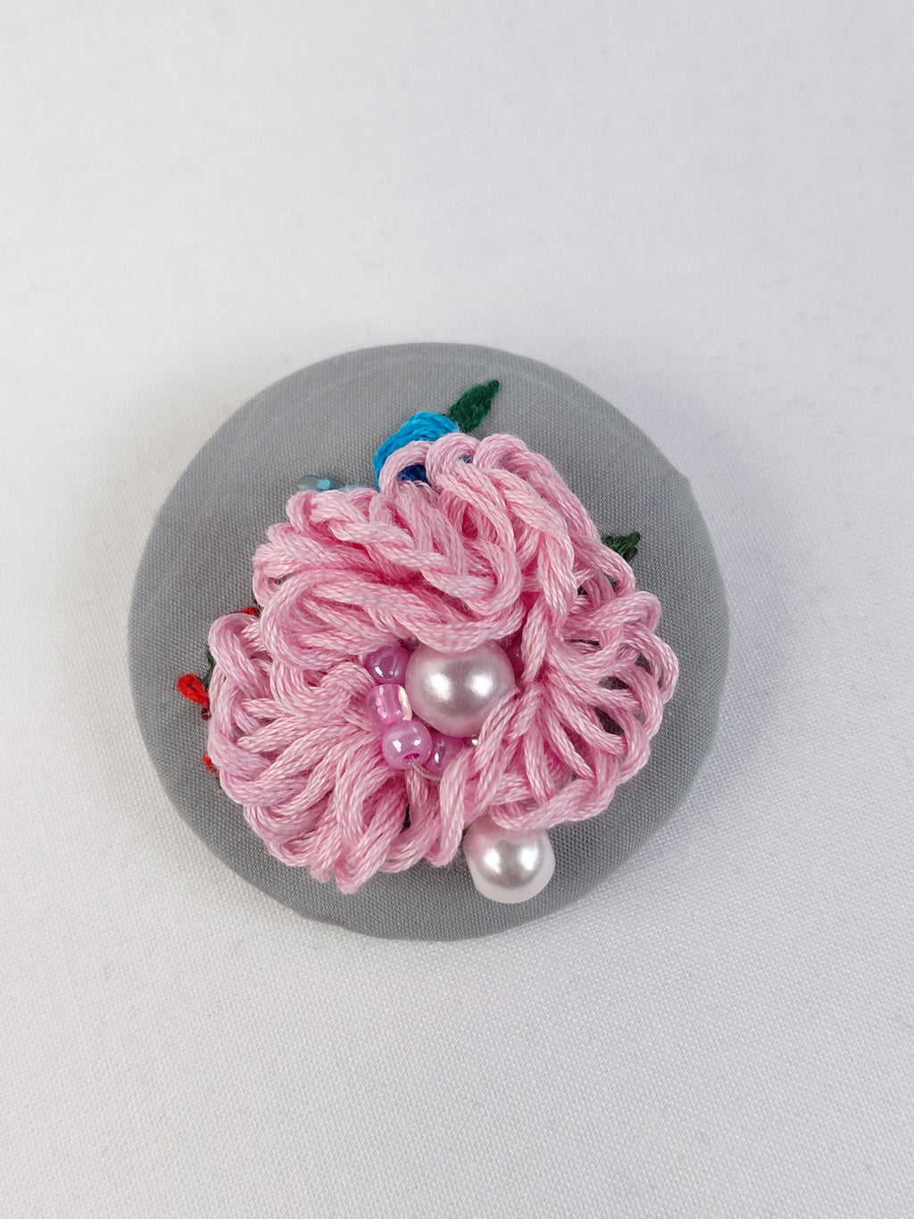 Decorative pink flower brooch on grey background