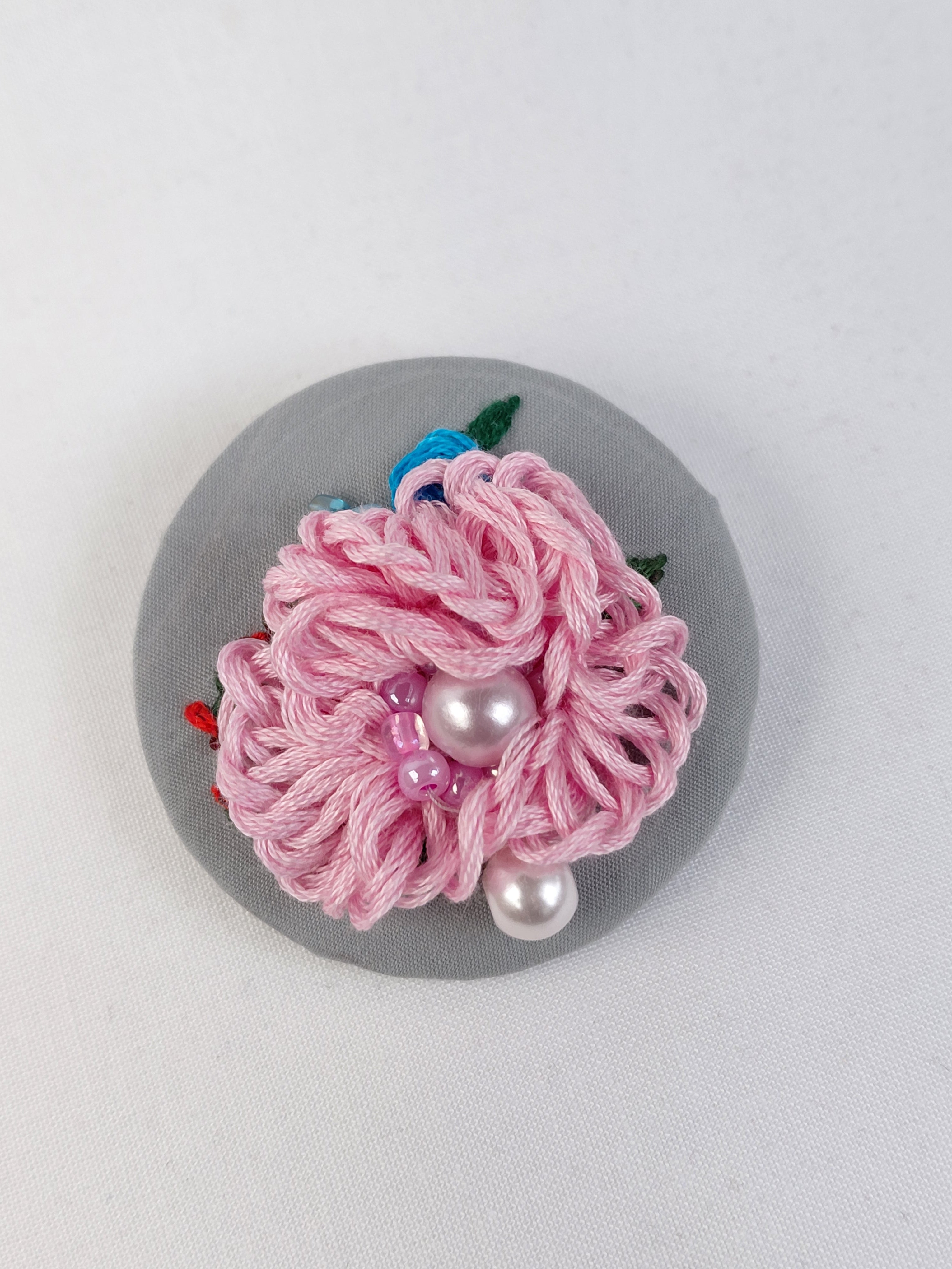 Decorative pink flower brooch on grey background