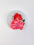 Decorative pink flower brooch on light blue with specs background