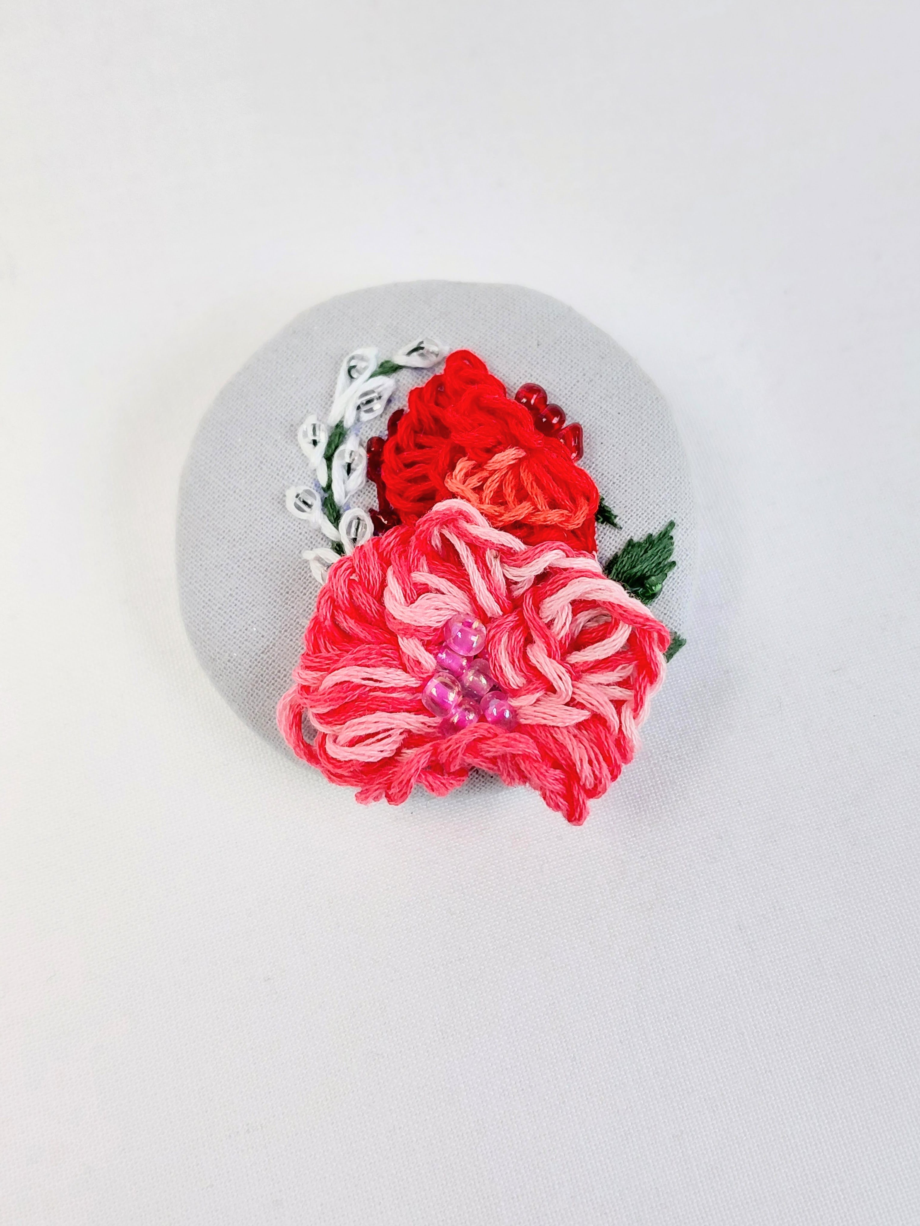 Decorative pink flower brooch on light blue with specs background