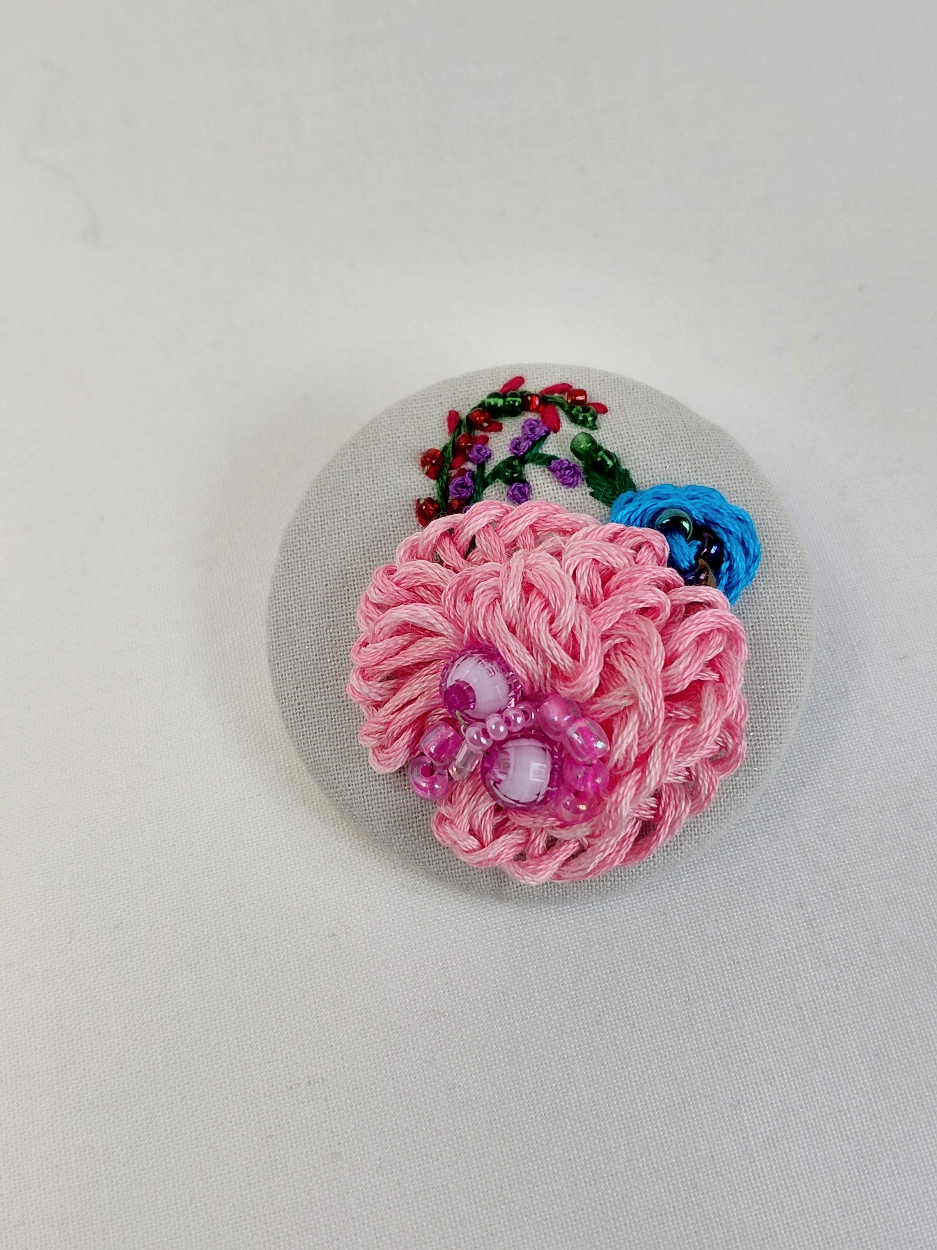 Decorative pink flower brooch on grey with specs background
