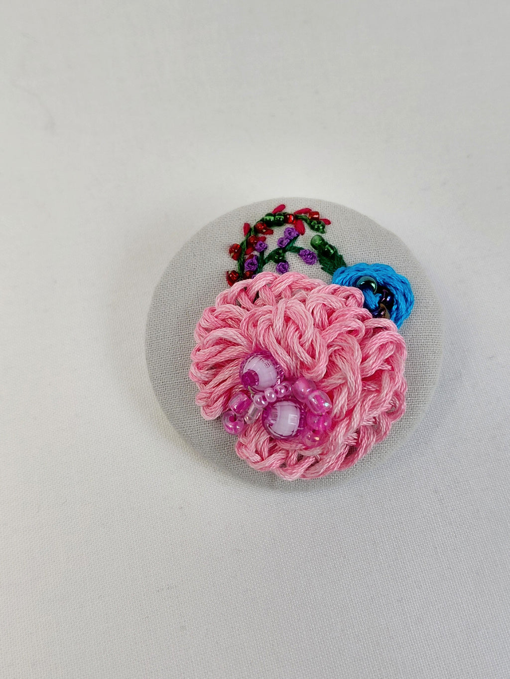 Decorative pink flower brooch on grey with specs background